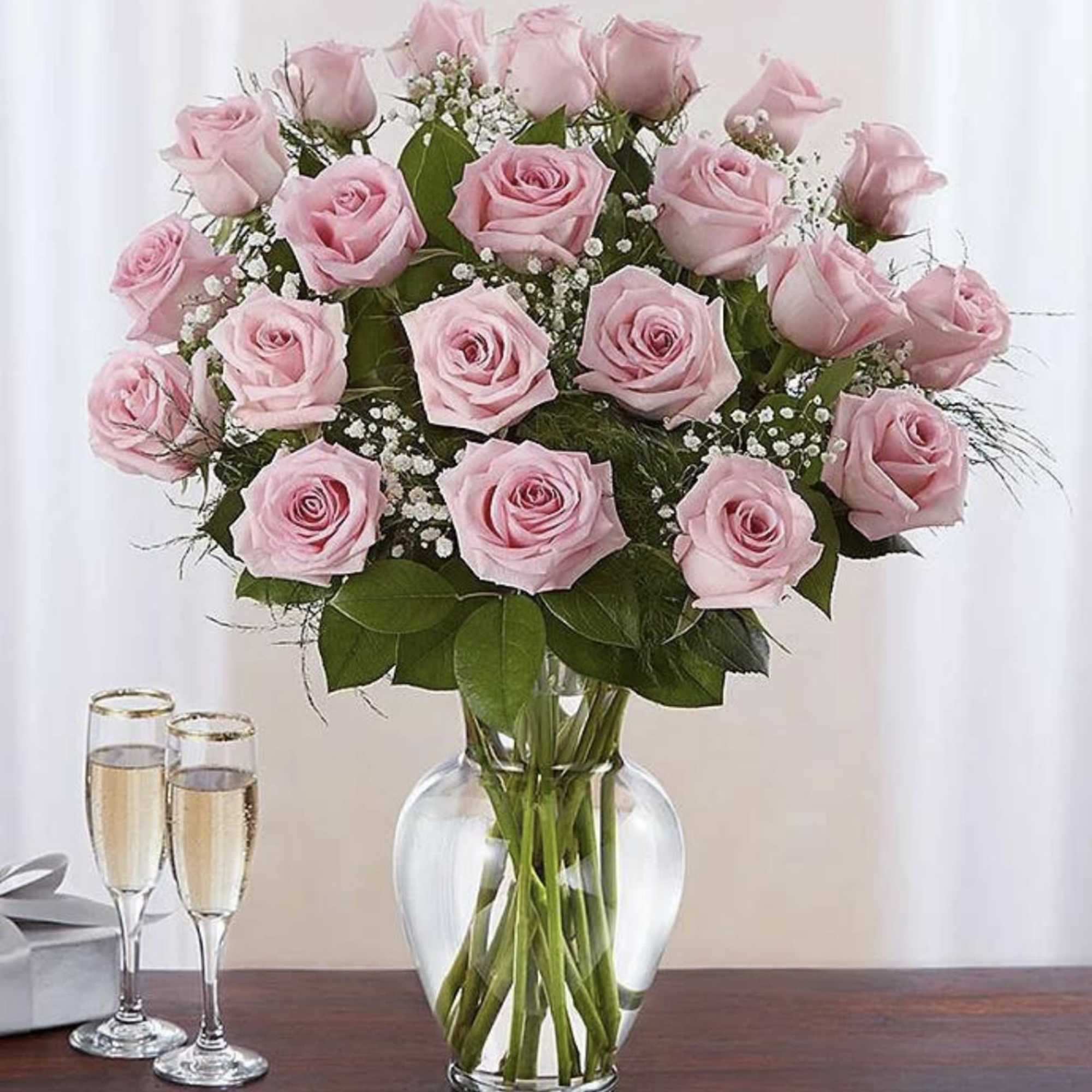 Pink roses arranged in a clear glass vase with baby's breath