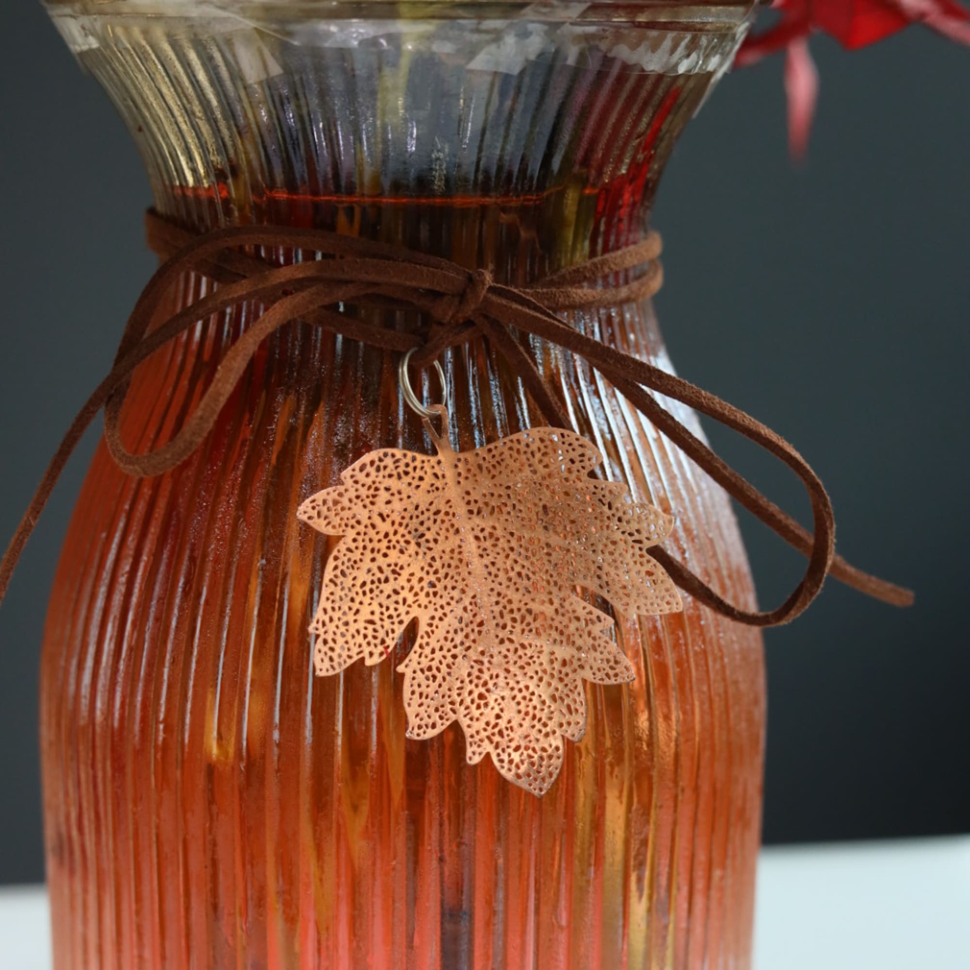 Amber ribbed glass vase tied with brown ribbon and a leaf charm