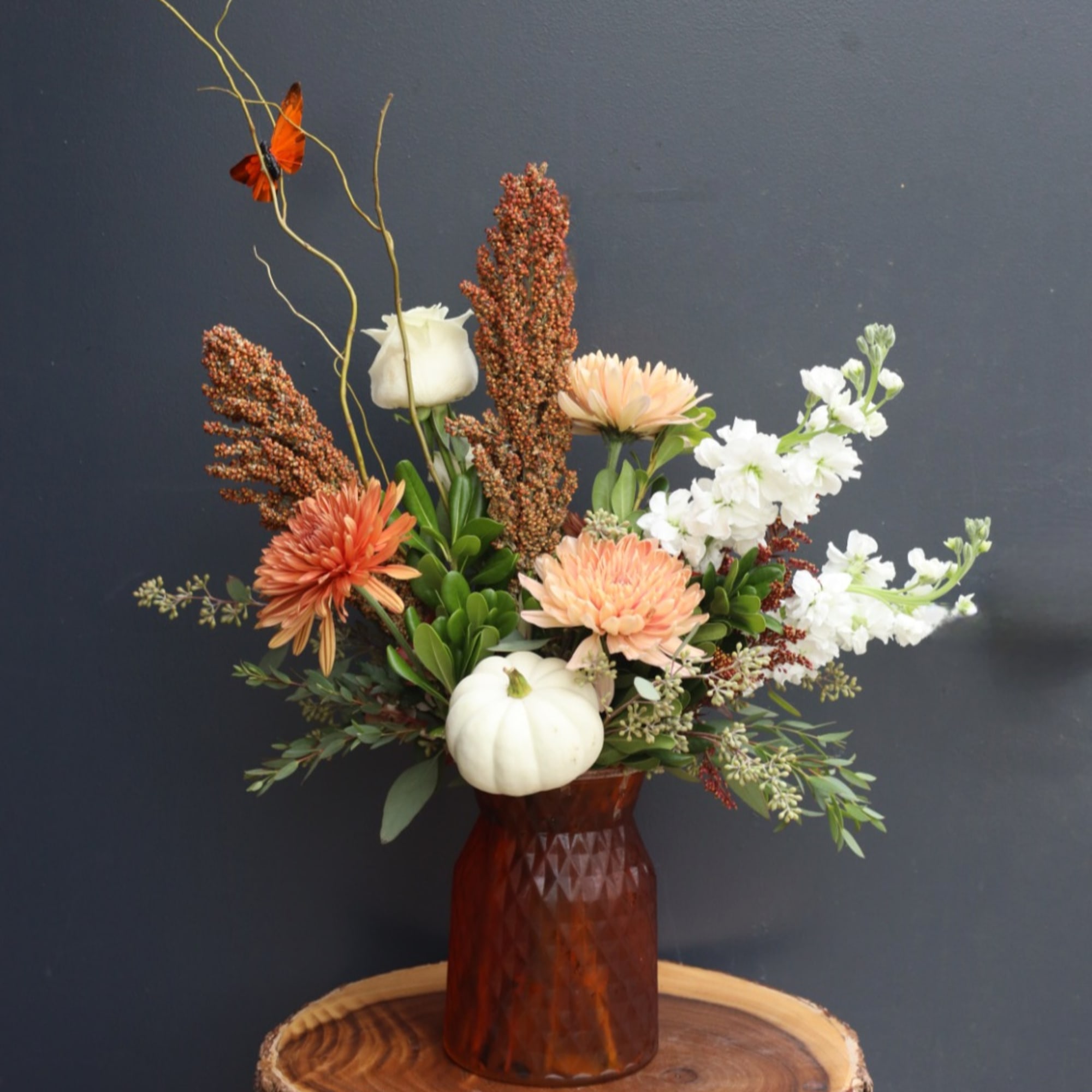 Autumn floral arrangement with white pumpkins in a brown vase