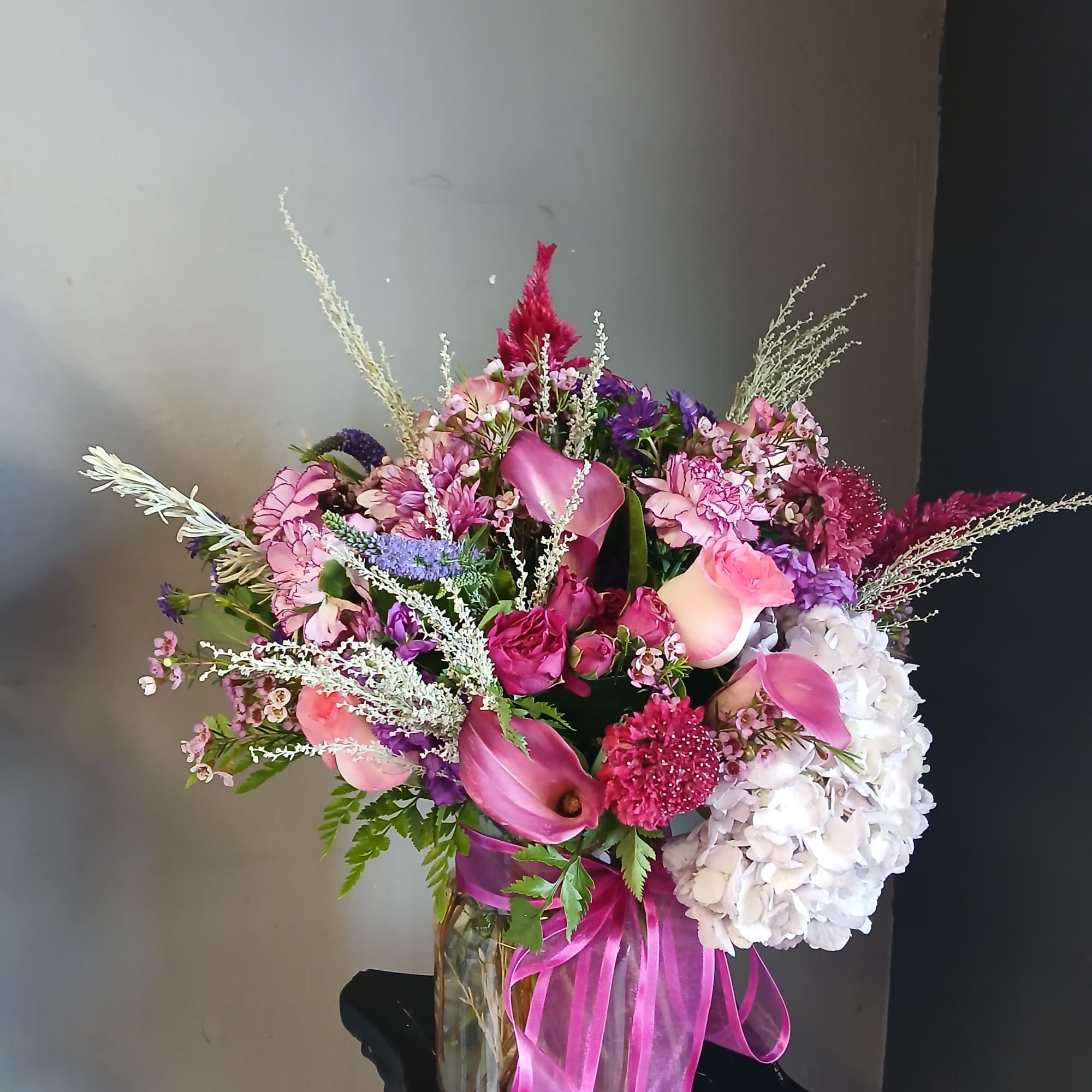 Pink and purple mixed bouquet in a glass vase with a ribbon
