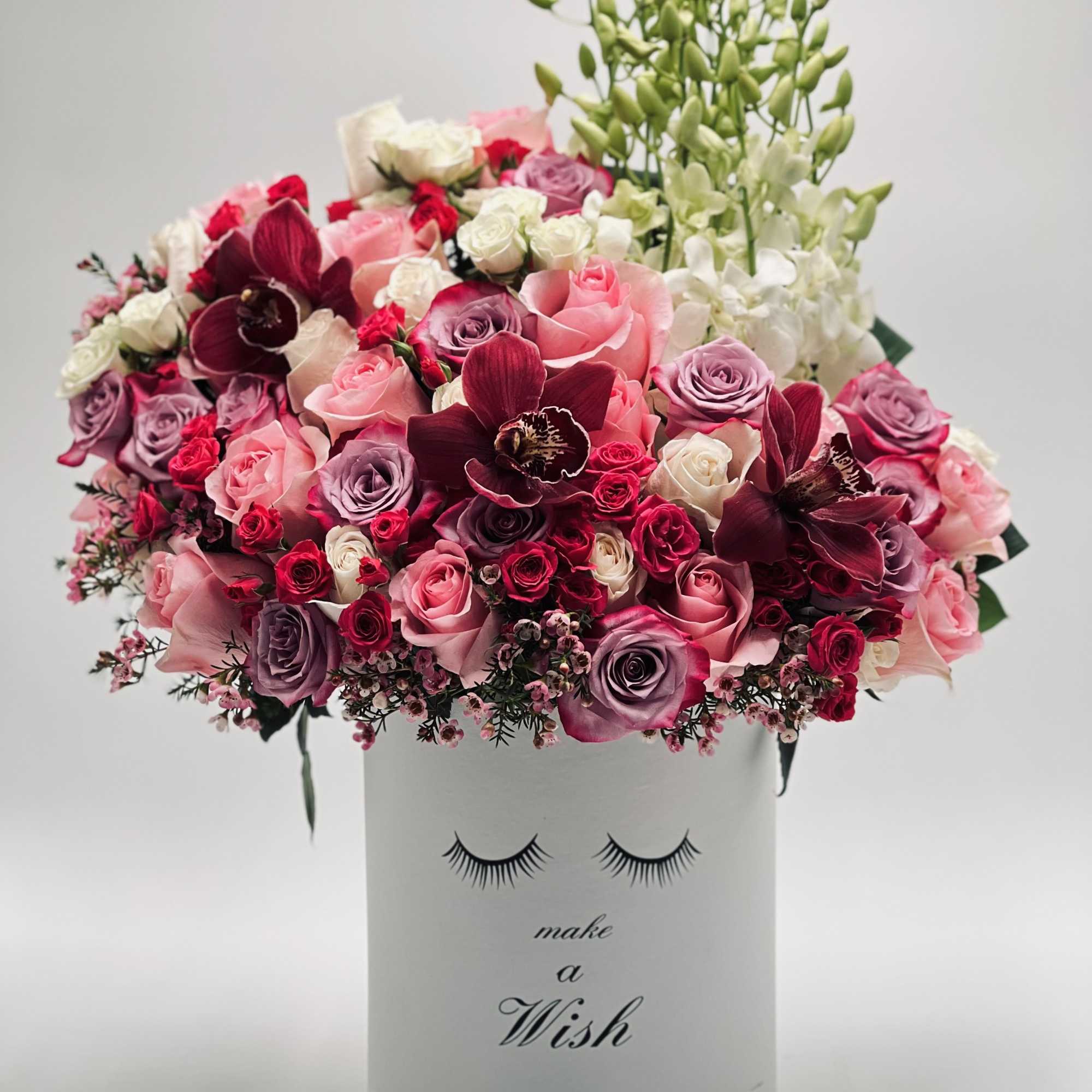 Pink and burgundy roses with orchids in a white box