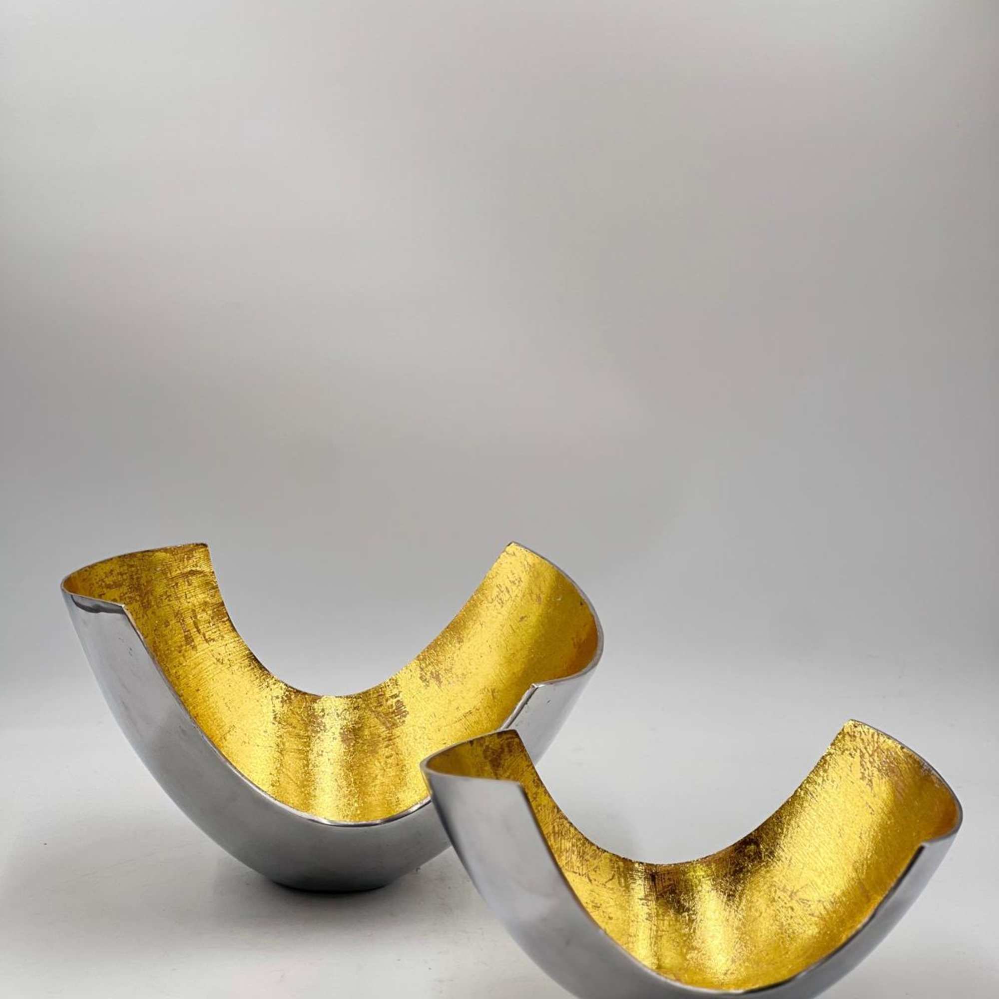 Two small gold and silver decorative bowls on a plain background