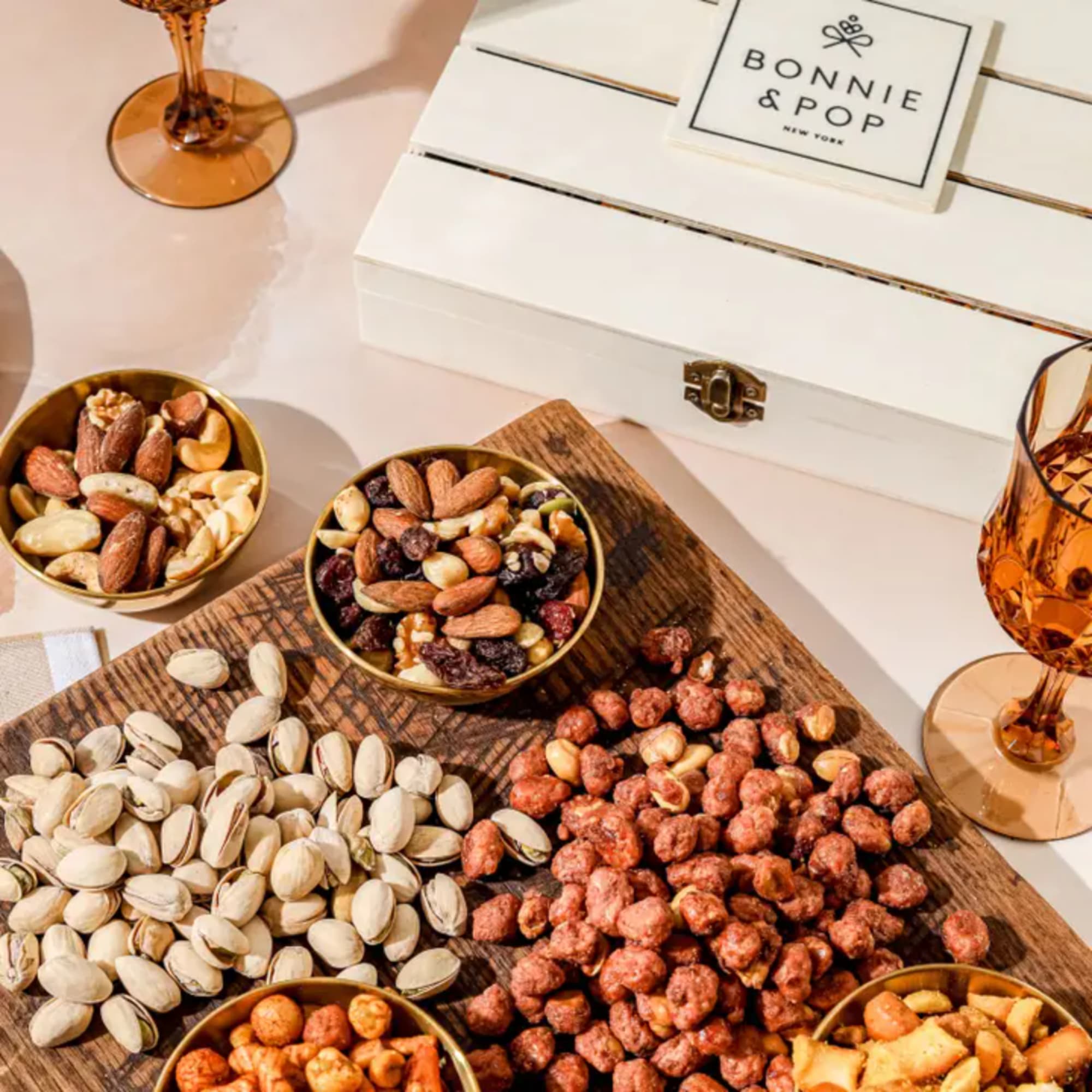 Assorted nuts and dried fruit in small bowls on a serving board