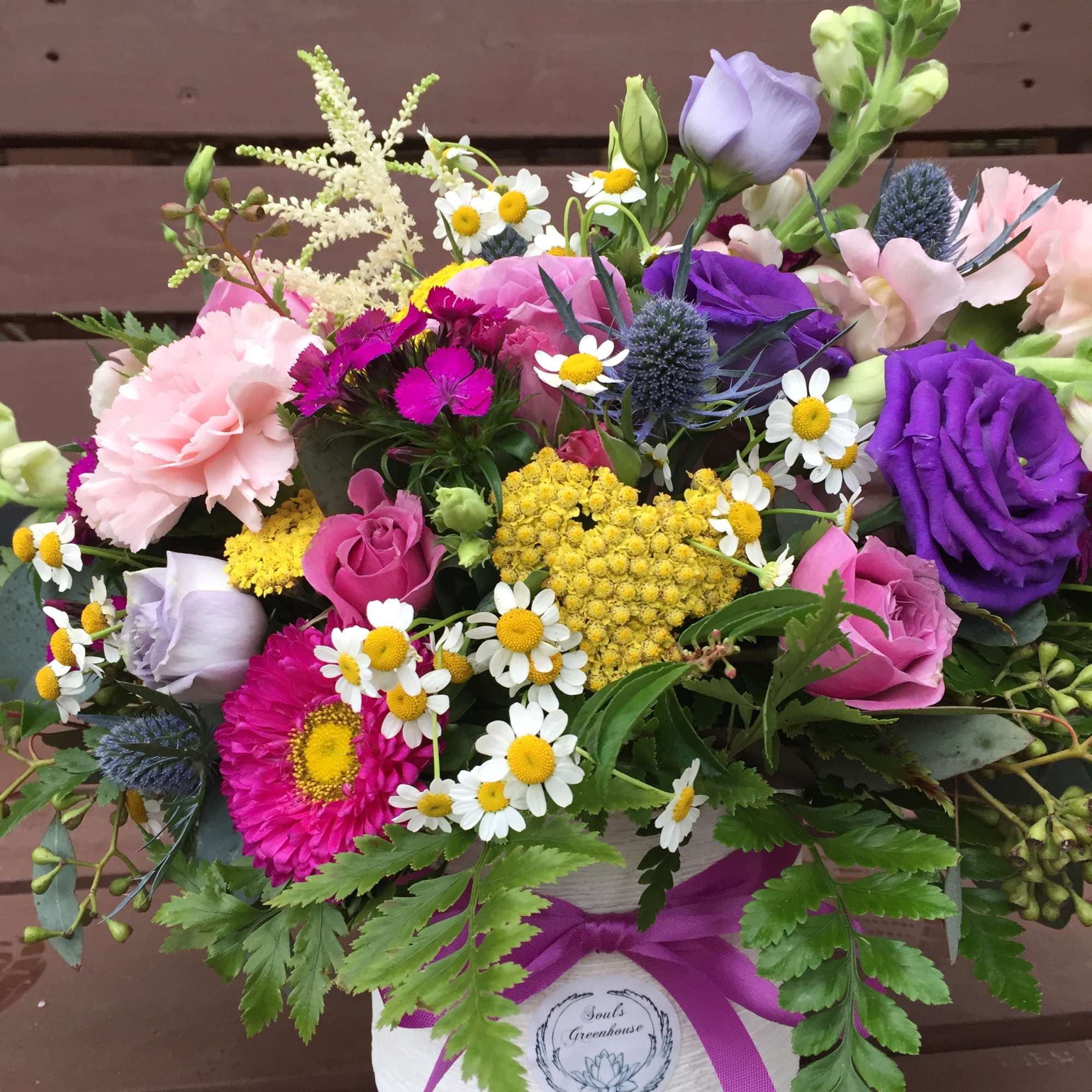 Mixed bouquet of pink, purple, and white flowers in a white hatbox with a ribbon