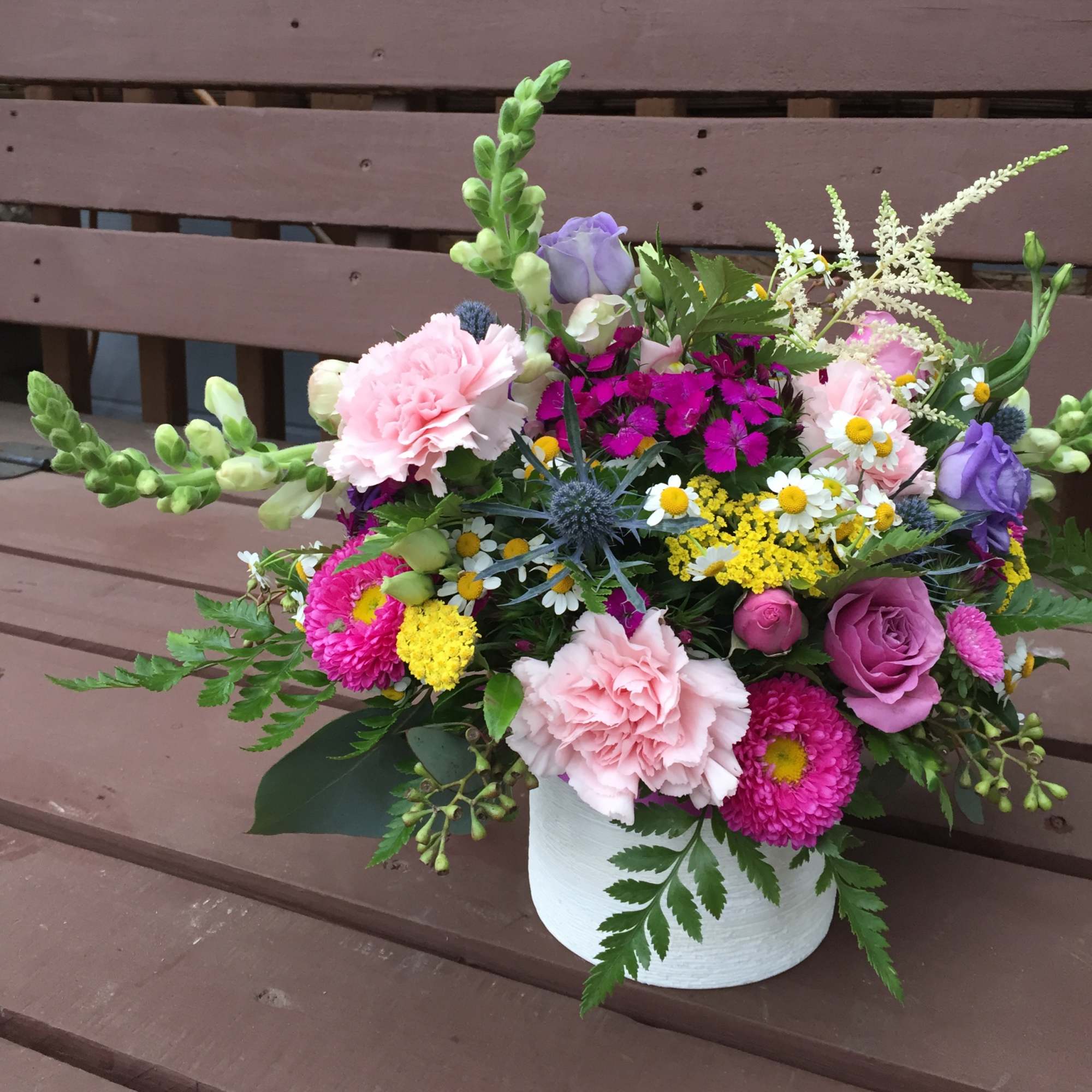 Colorful mixed flower arrangement in a white container