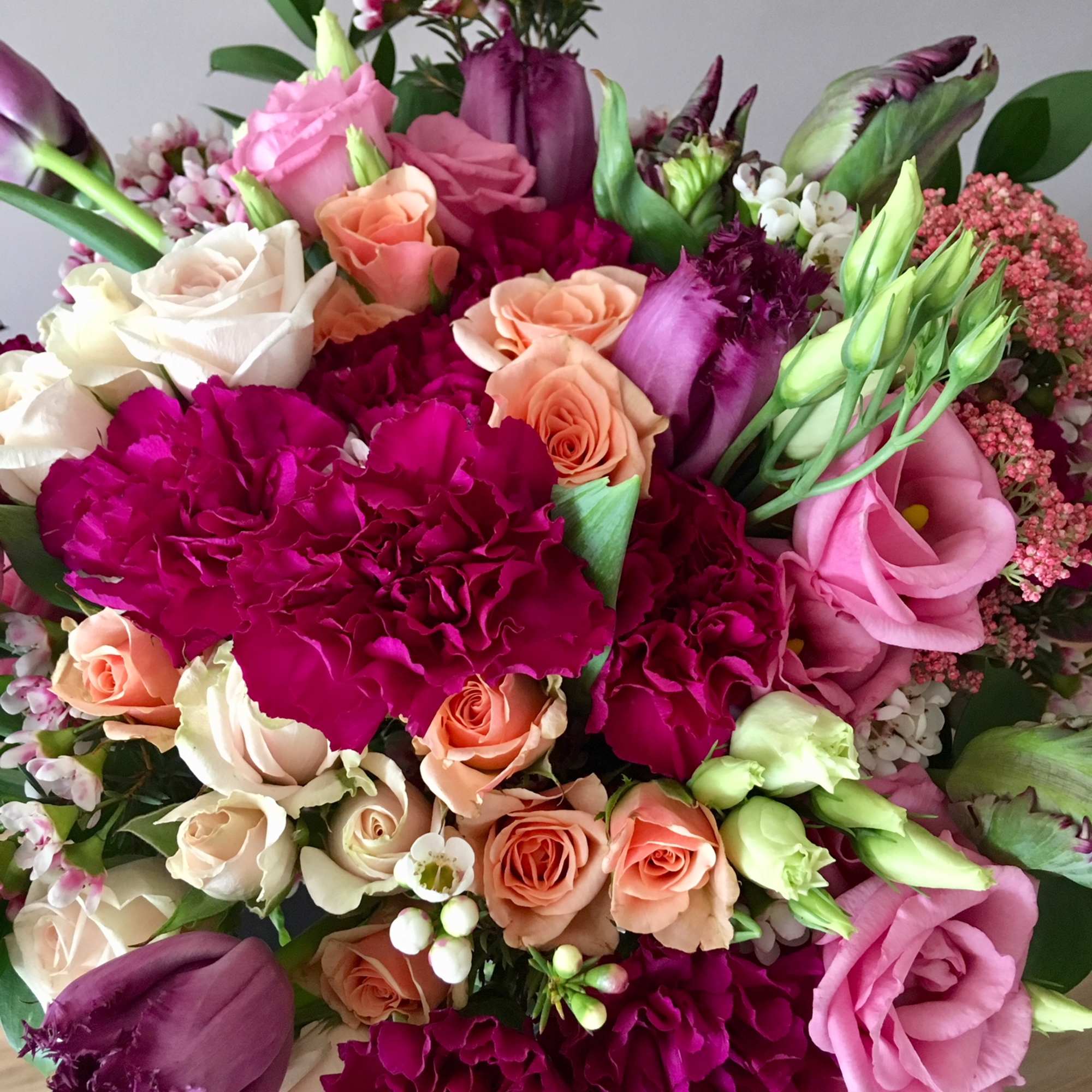 Bouquet of pink, peach, and white roses with magenta carnations