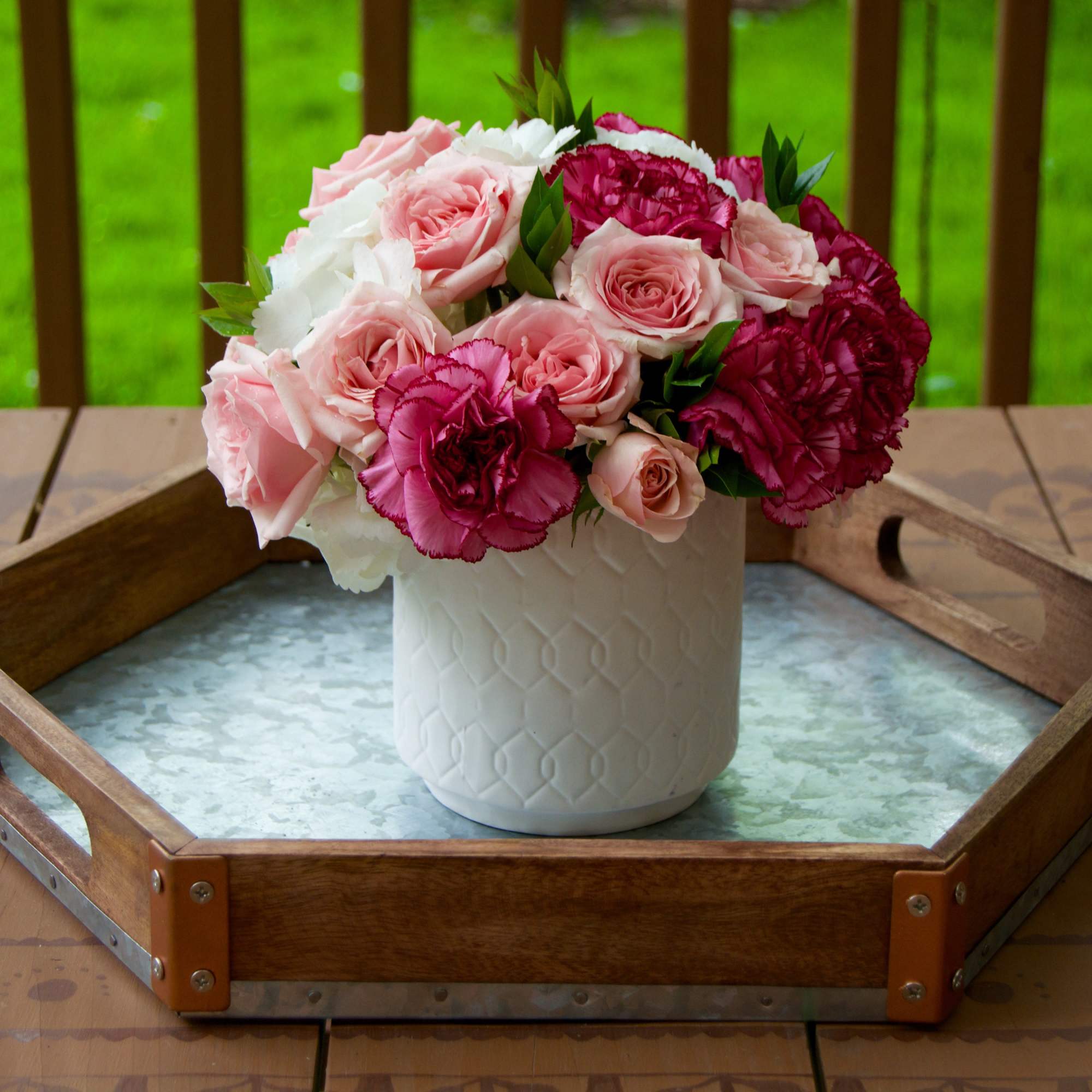 Pink and white roses with carnations in a white vase