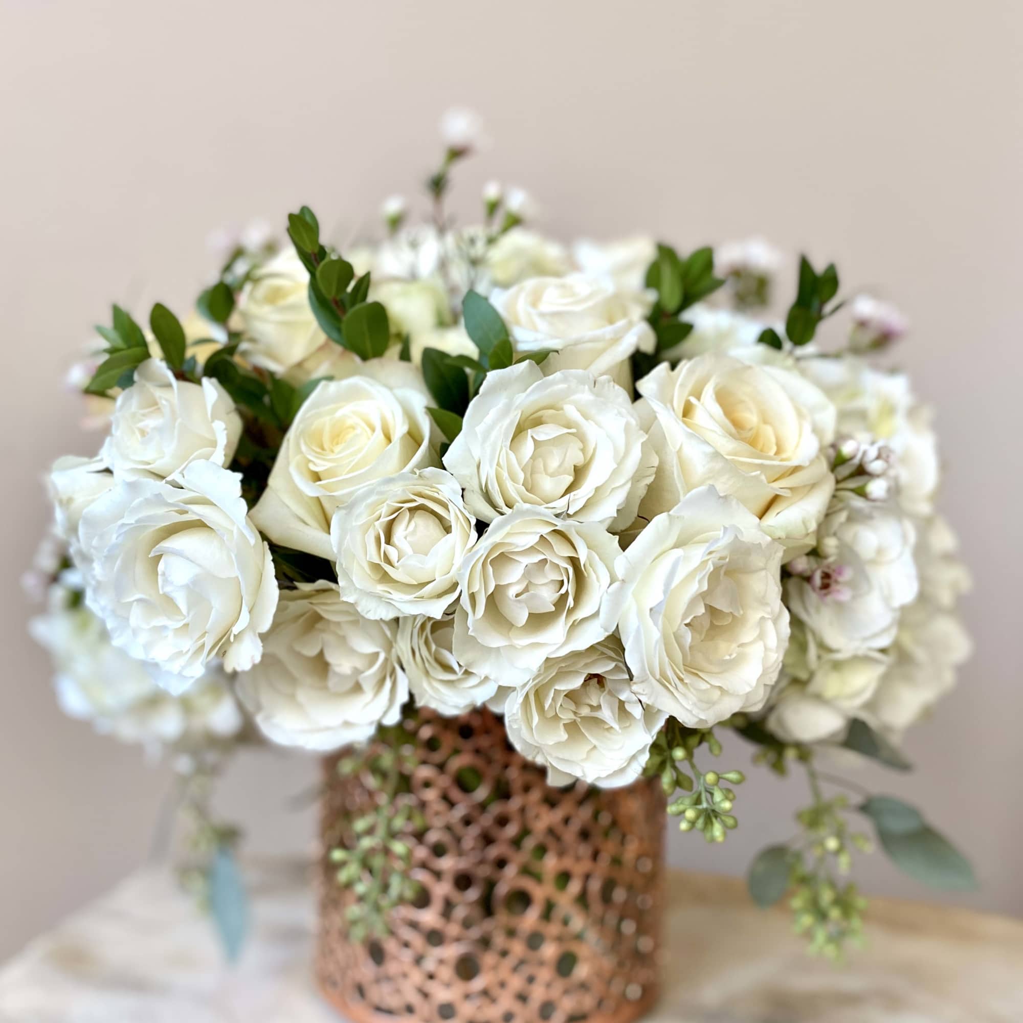 White rose bouquet in a patterned copper vase