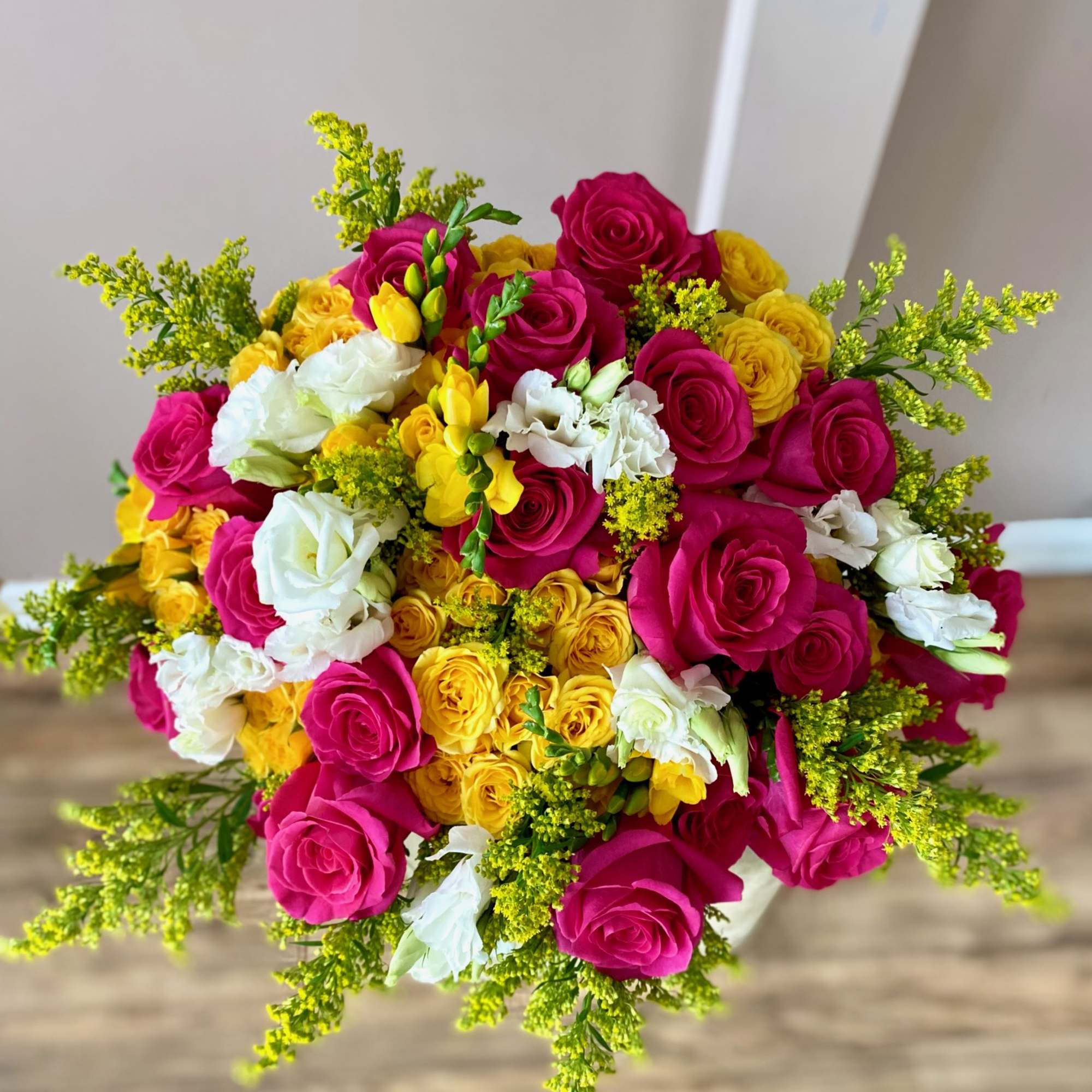 Bouquet of hot pink, yellow, and white roses with airy yellow filler
