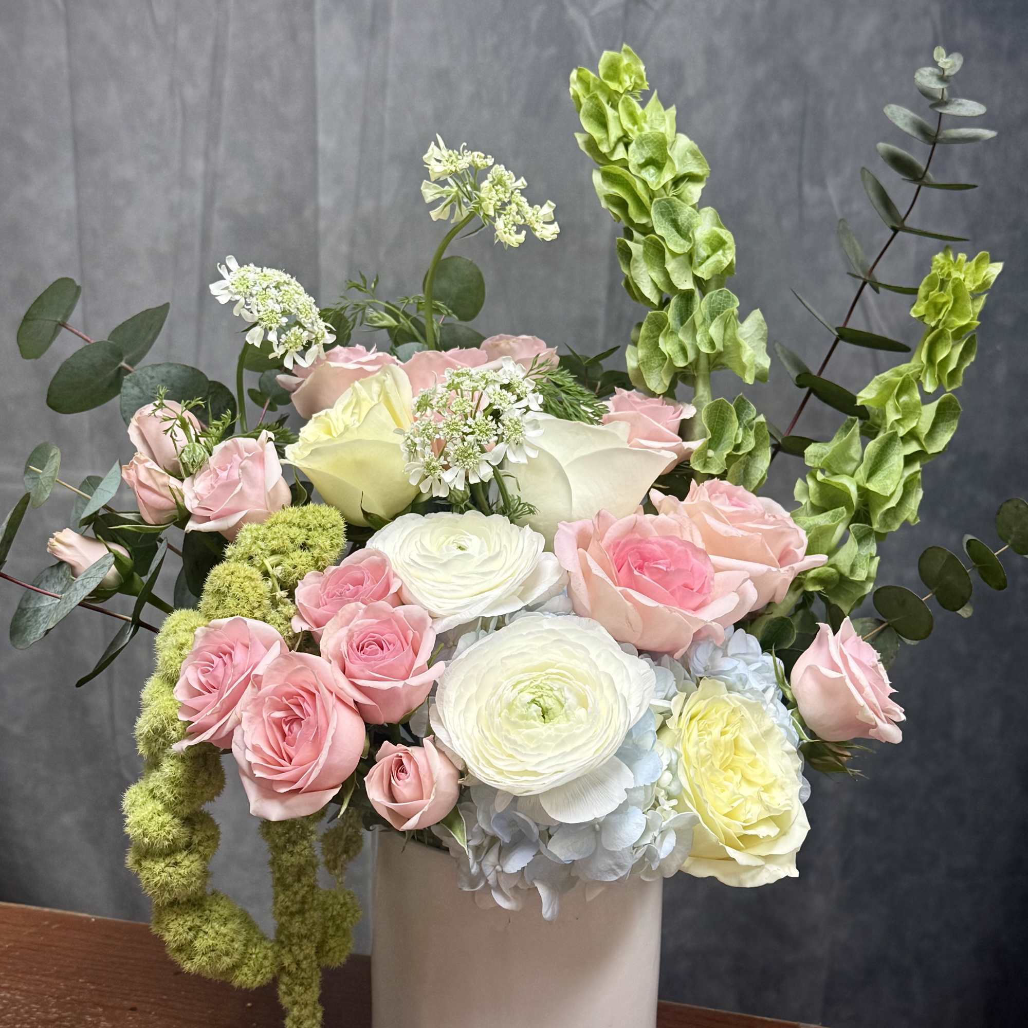 Pink and white roses with ranunculus in a white vase