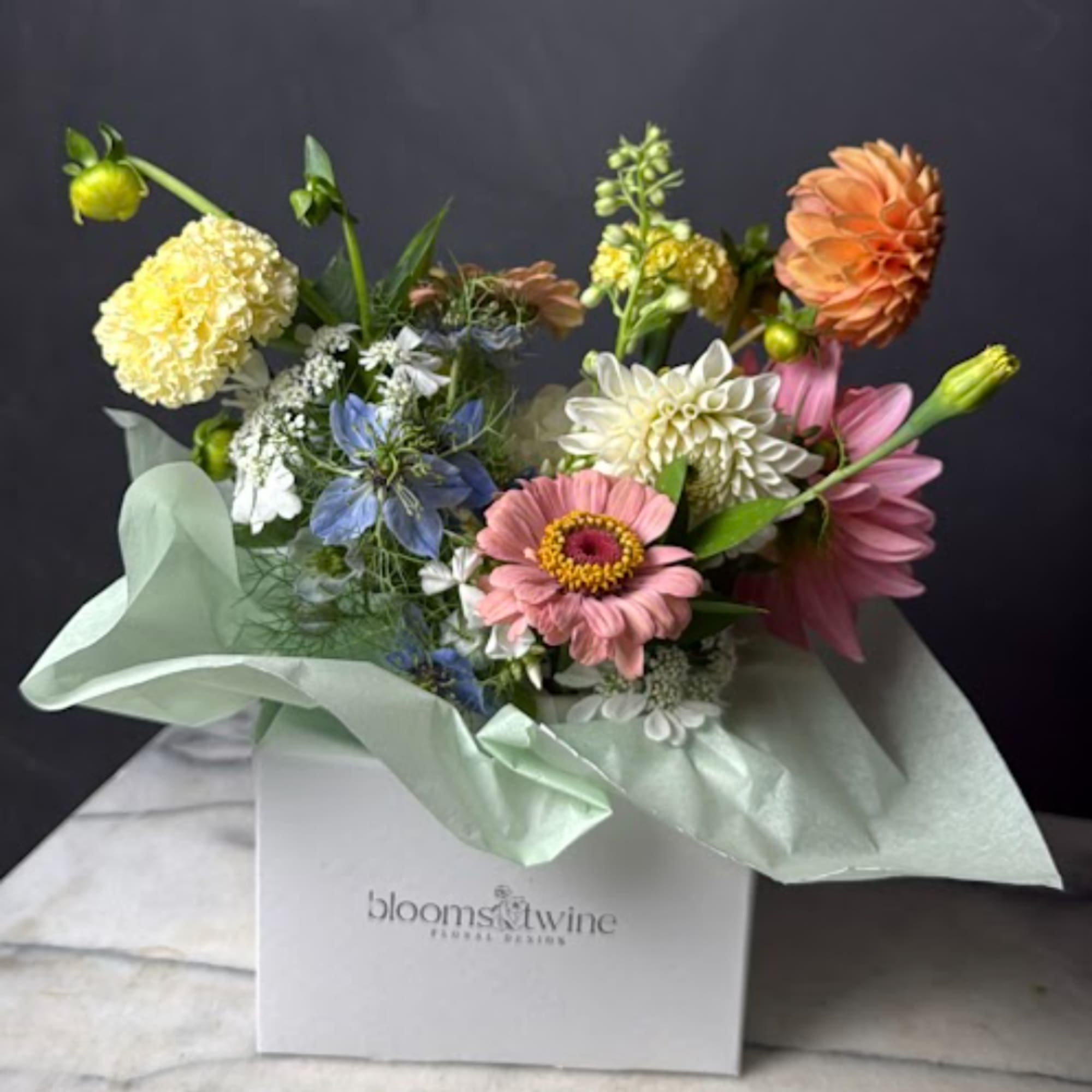 Mixed bouquet with pink, peach, yellow, and white flowers in a gift box