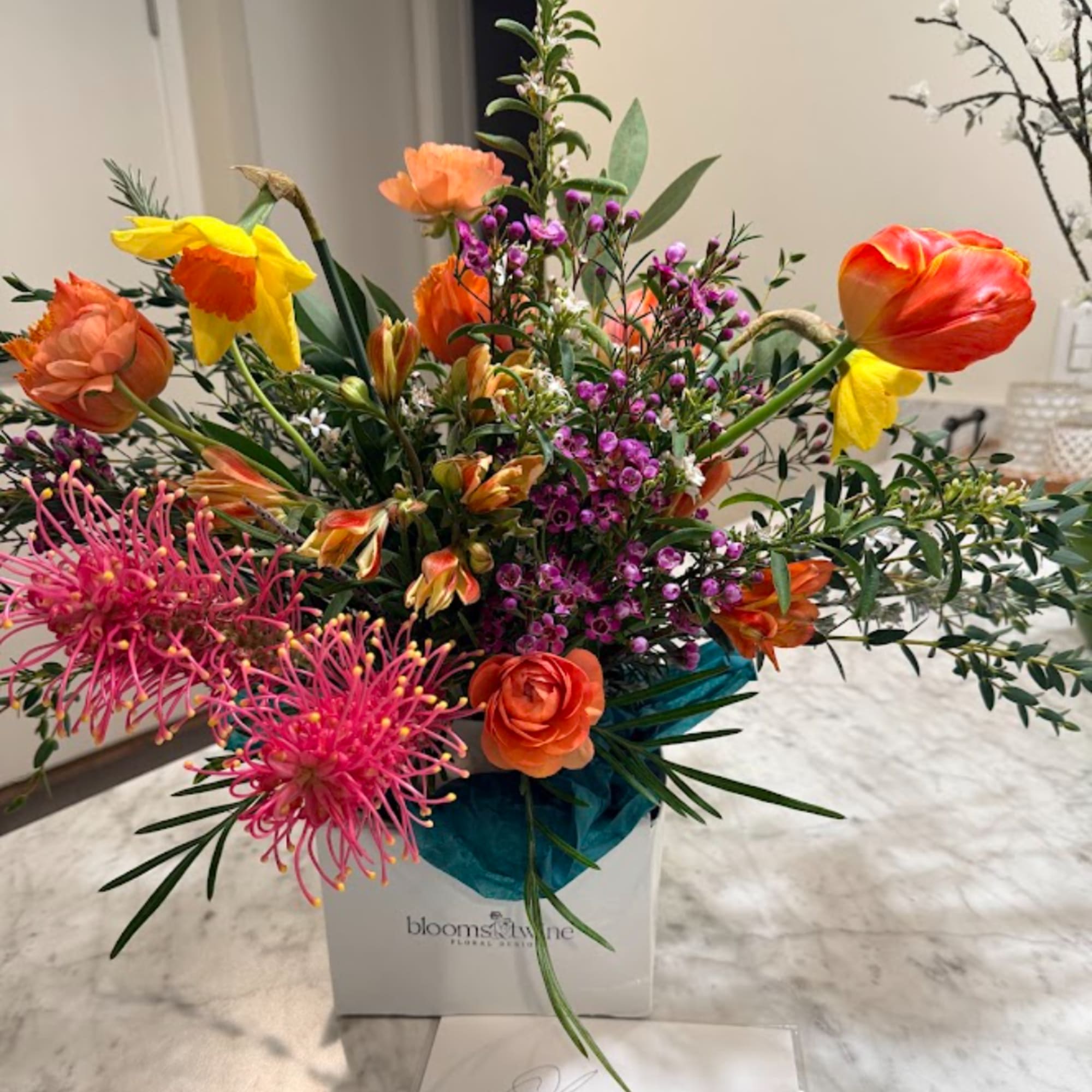 Bright mixed bouquet with orange and yellow blooms in a white box