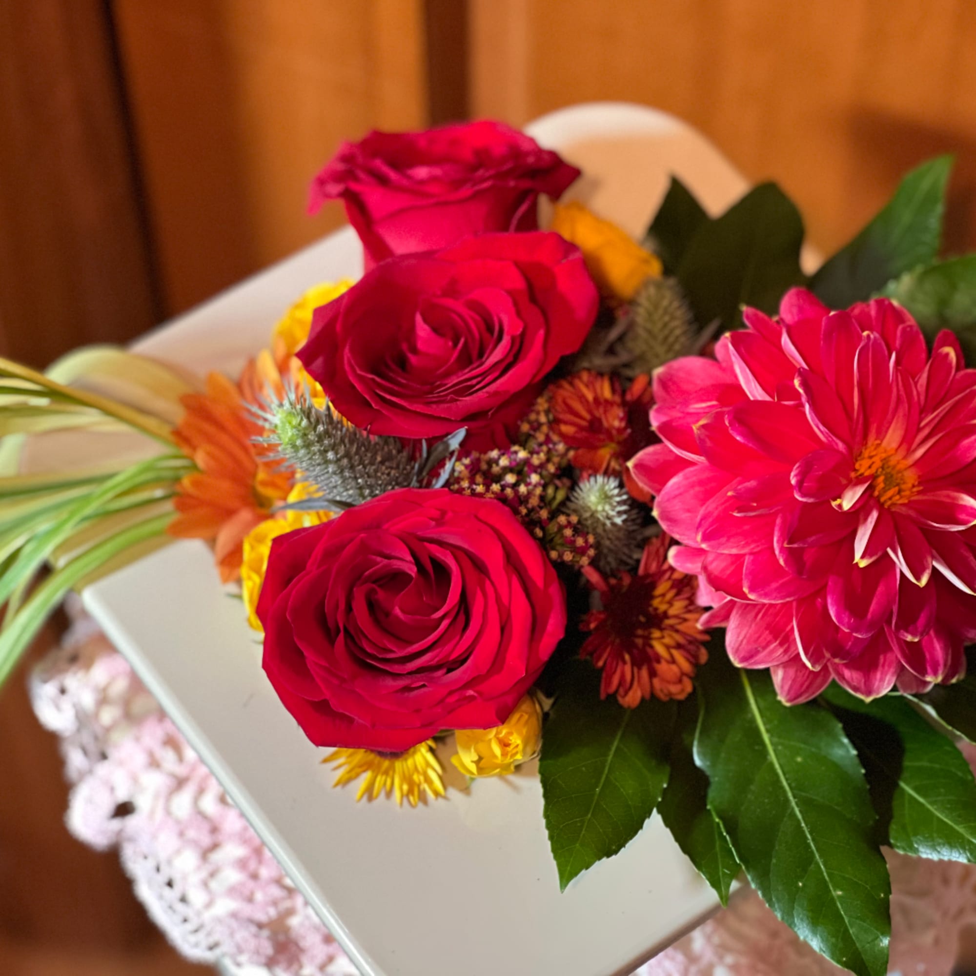 Mixed bouquet with red roses and a bright pink dahlia in a white box