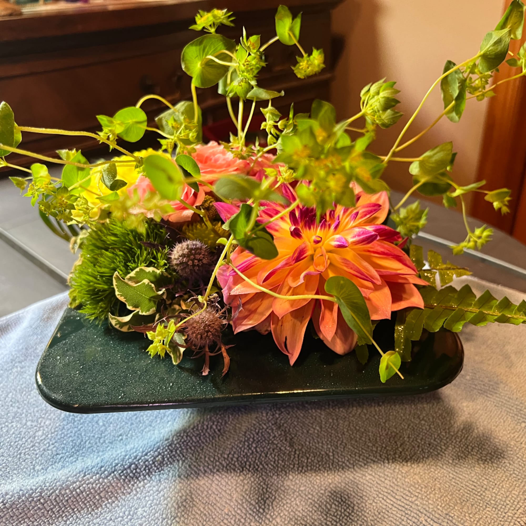 Colorful floral arrangement in a dark rectangular vase with orange and pink blooms
