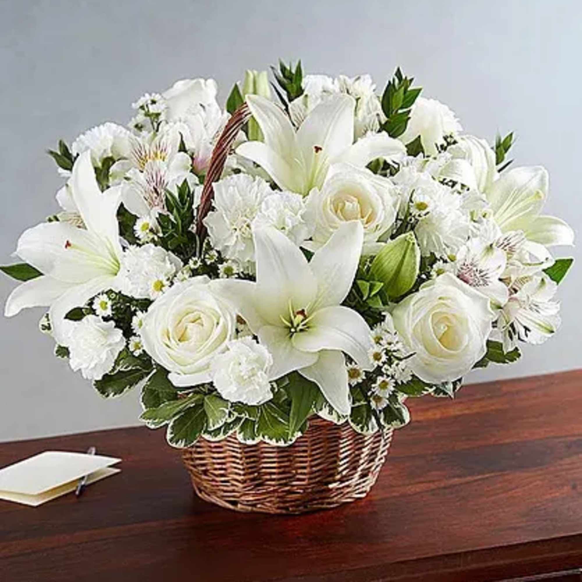 White lilies and roses arranged in a wicker basket