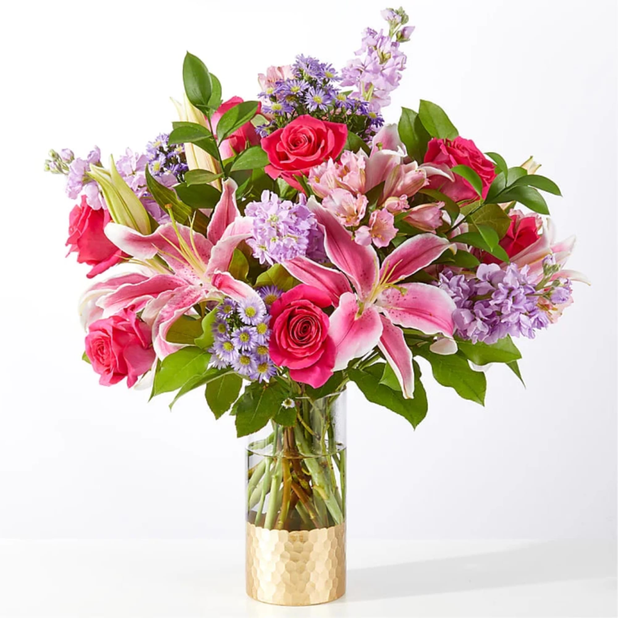 Pink roses and lilies in a glass vase with purple flowers