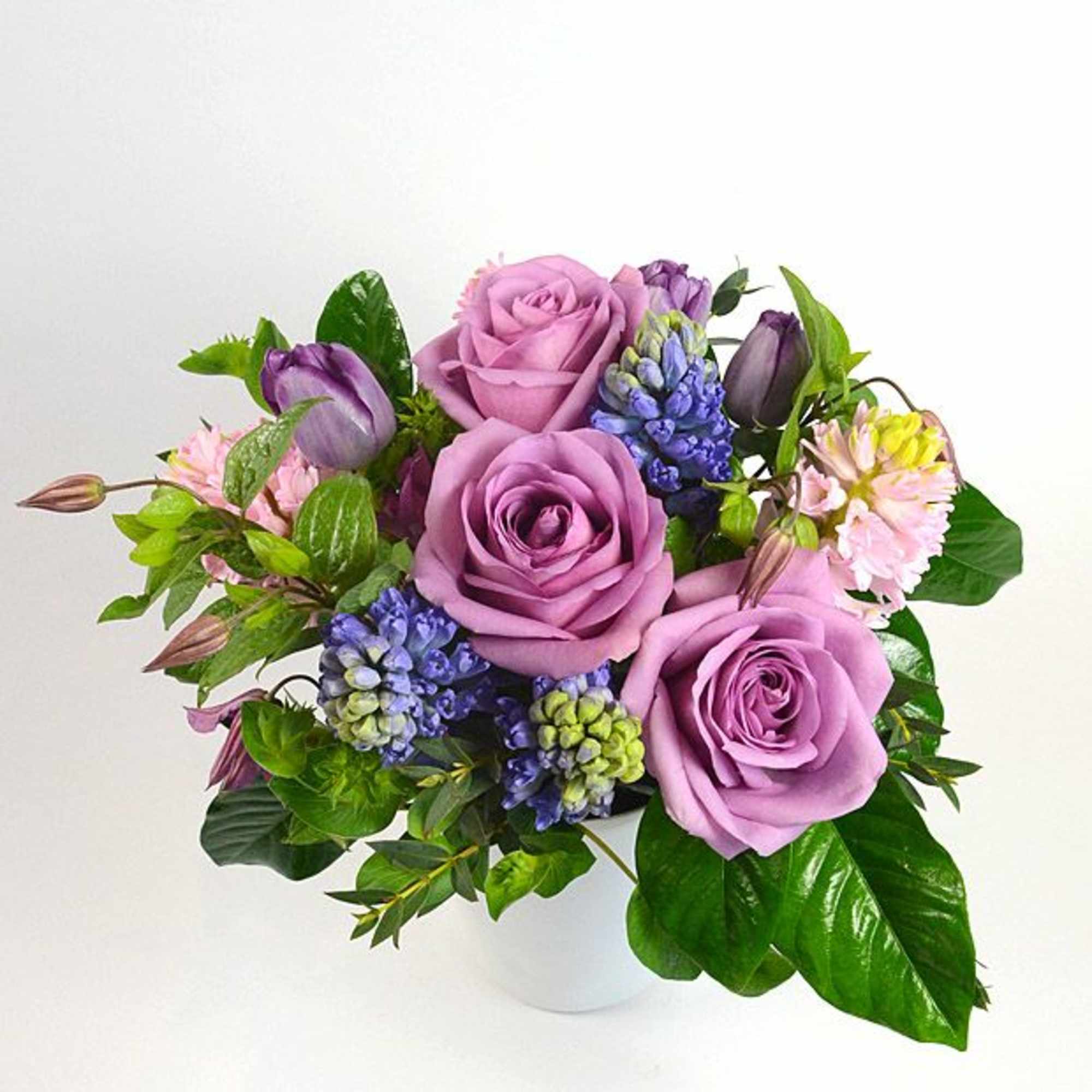 Lavender roses with purple tulips and blue flowers in a white vase