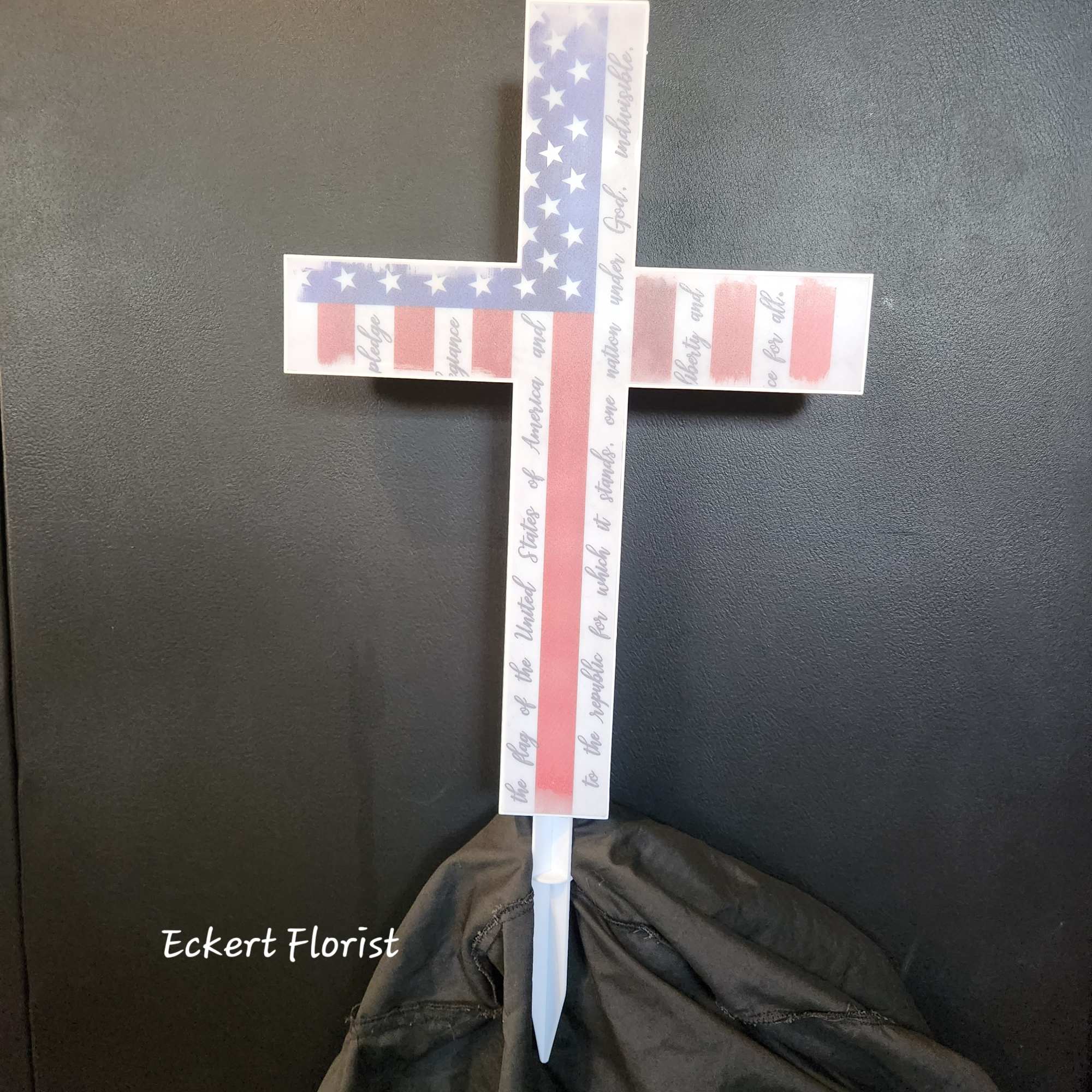 American flag cross-shaped memorial stake with a white base