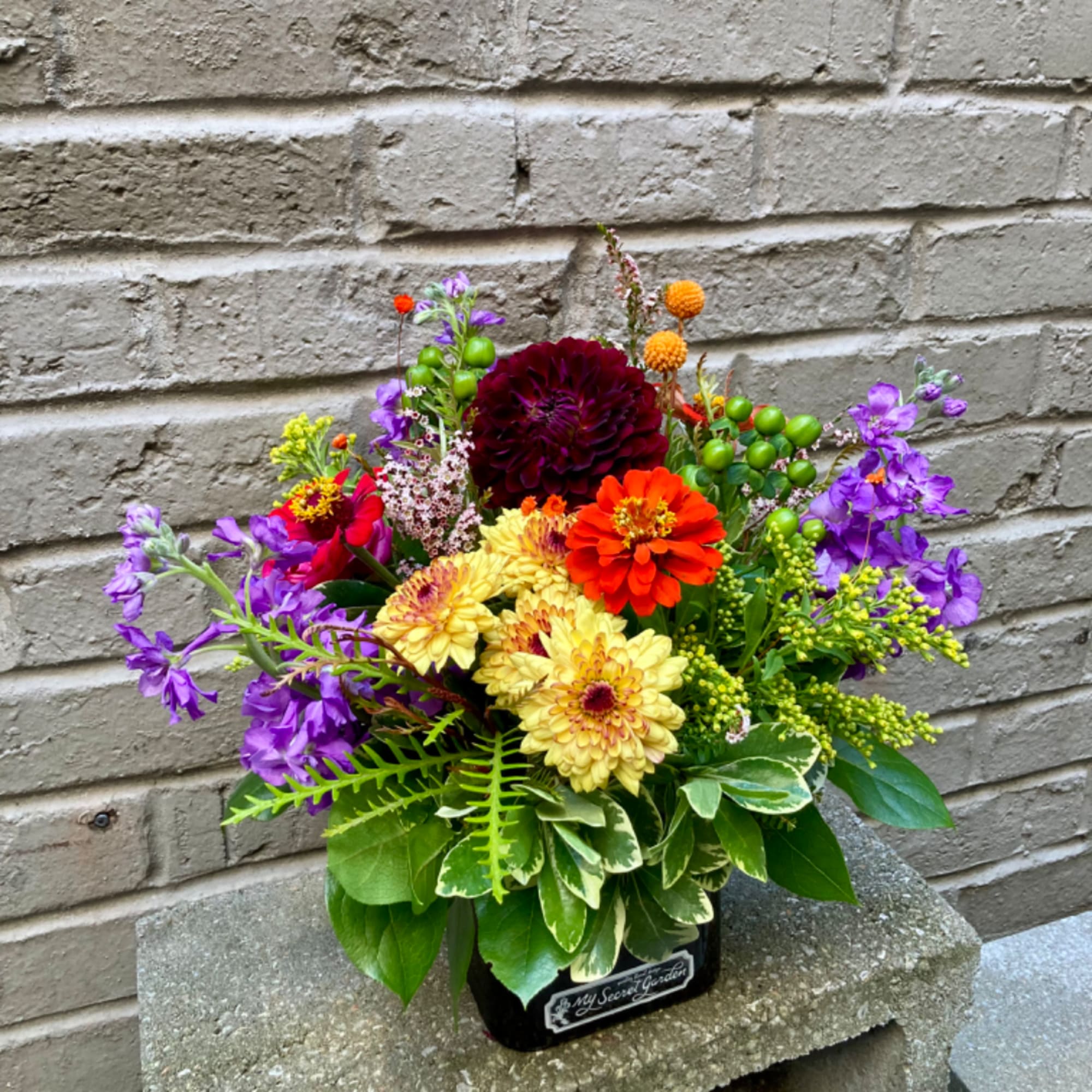 Colorful mixed flower arrangement in a black container