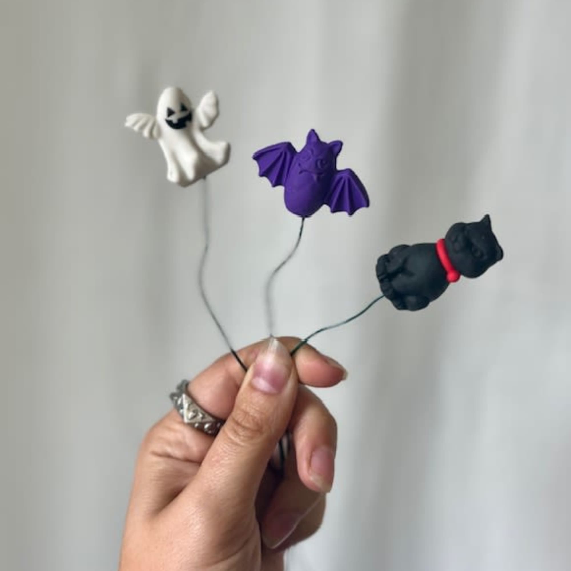 Hand holding three small Halloween ghost and bat picks