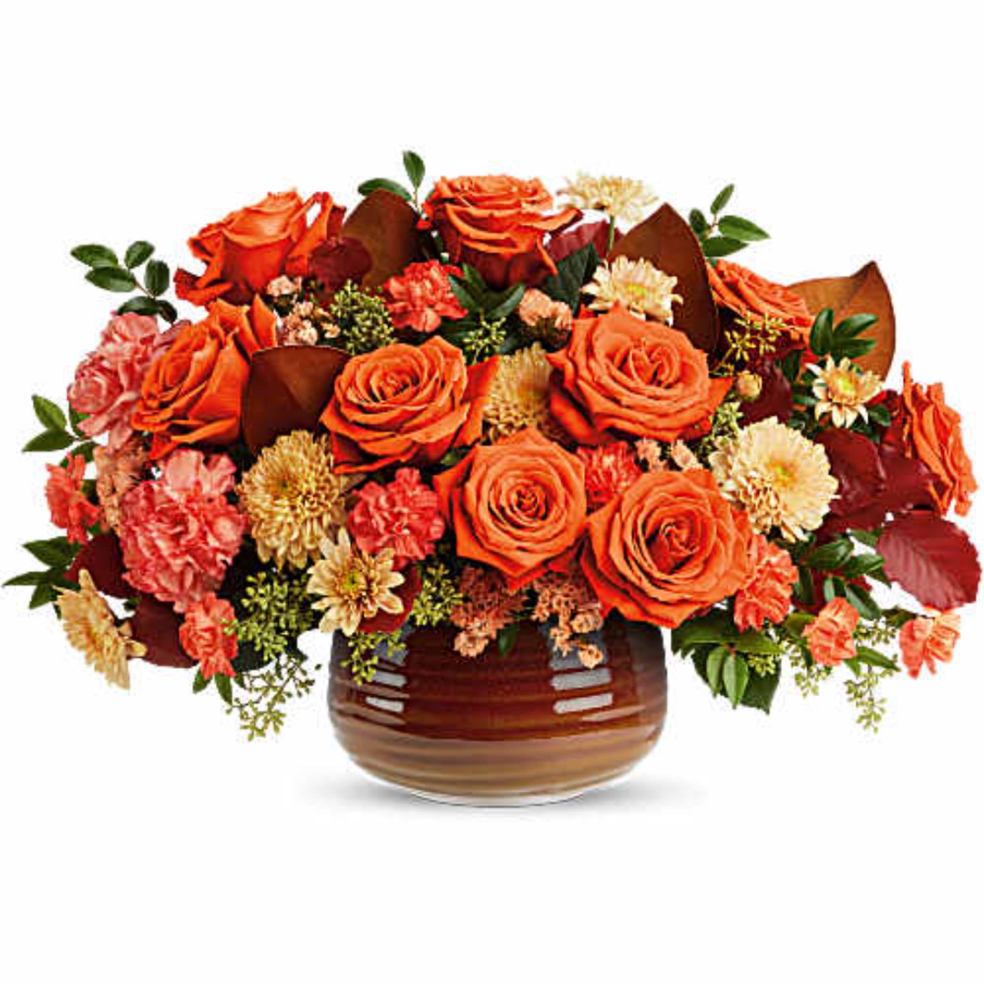 Orange roses and mixed flowers arranged in a brown vase