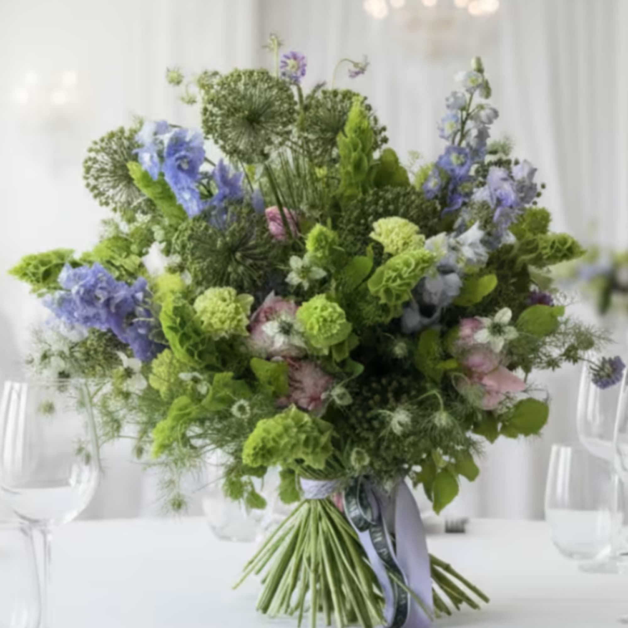 Large bouquet of blue and green flowers tied with ribbon