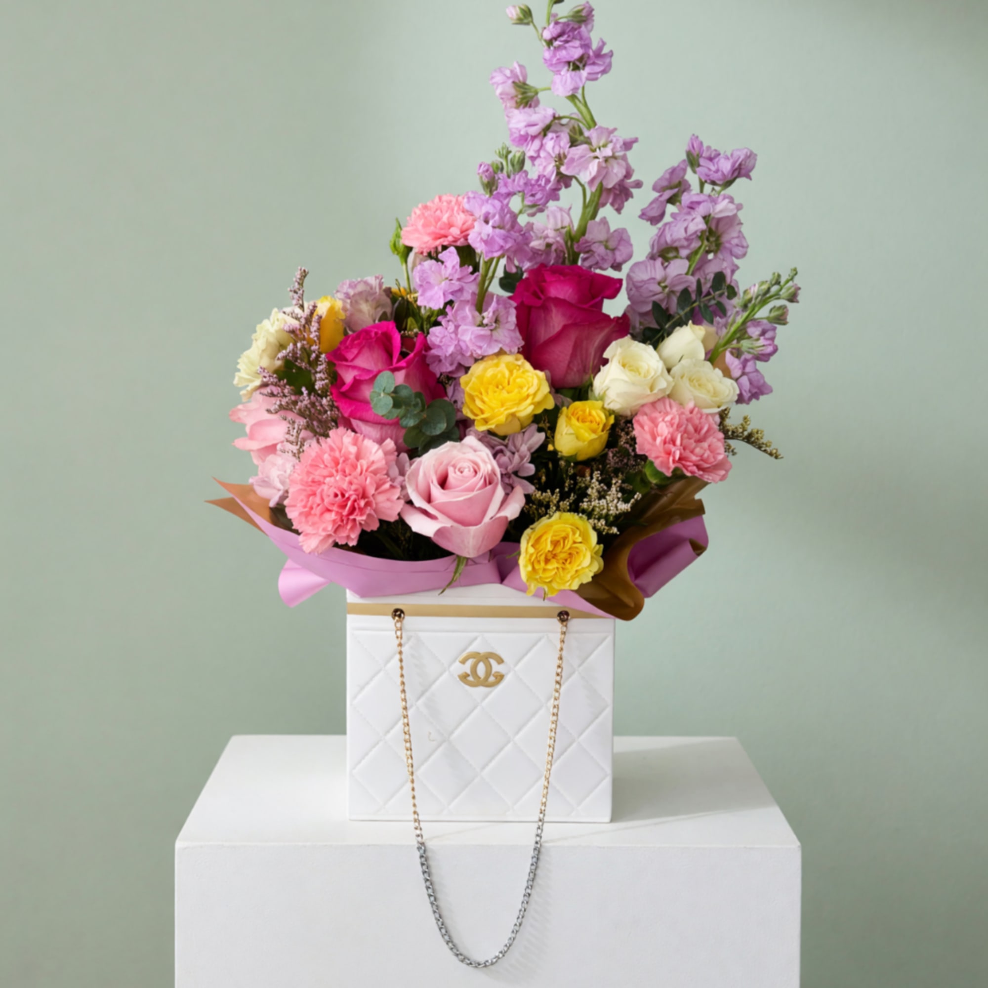 Mixed bouquet of pink, yellow, and lavender flowers in a white box