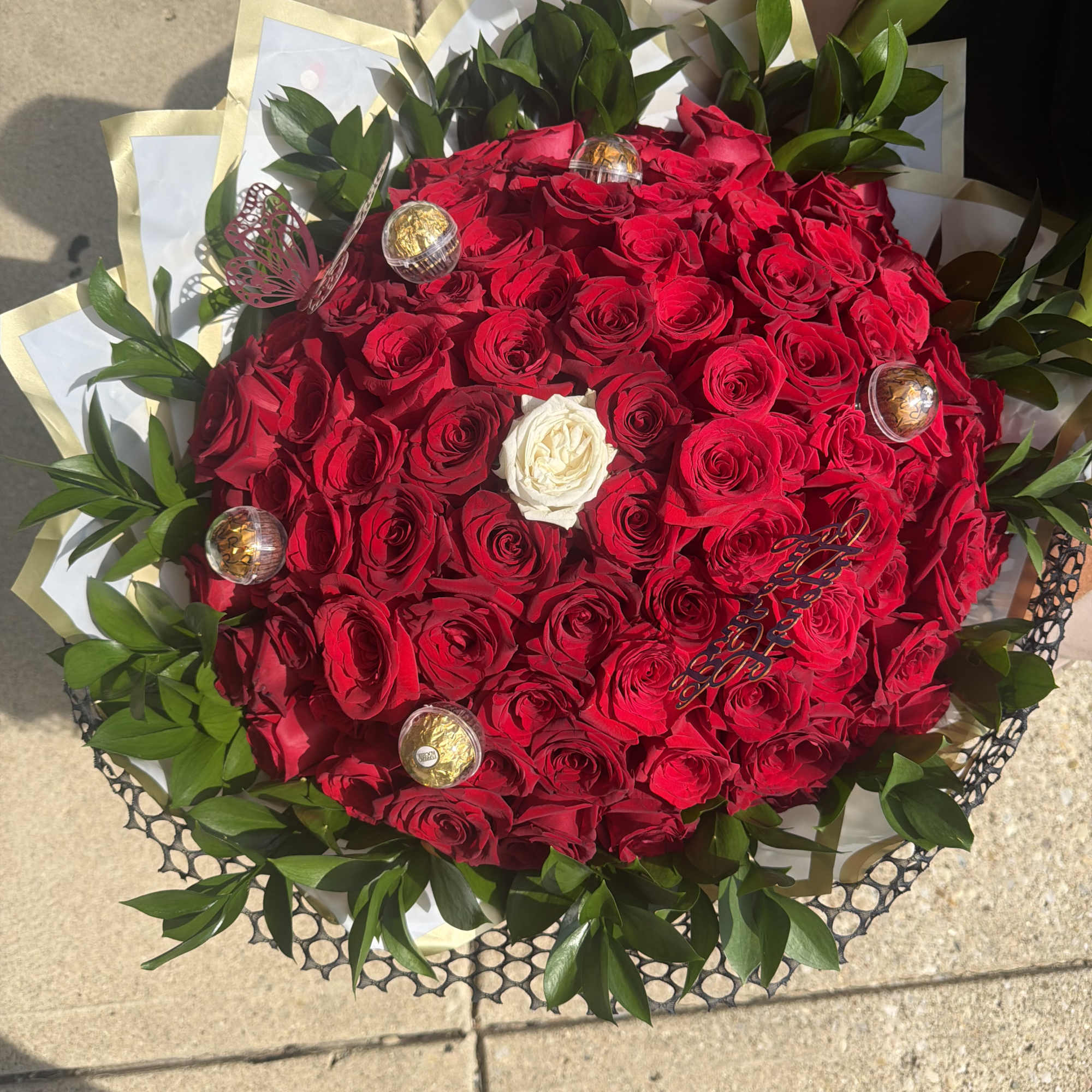 Large bouquet of red roses with a white rose center and green foliage