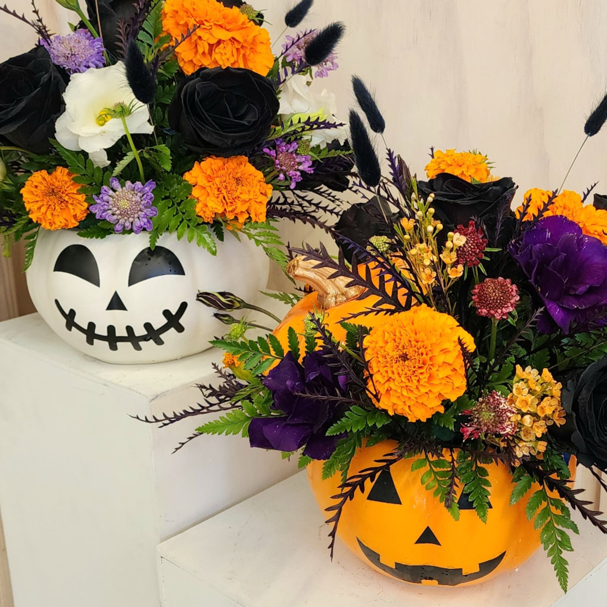 Halloween pumpkin containers filled with orange, black, purple, and white flowers