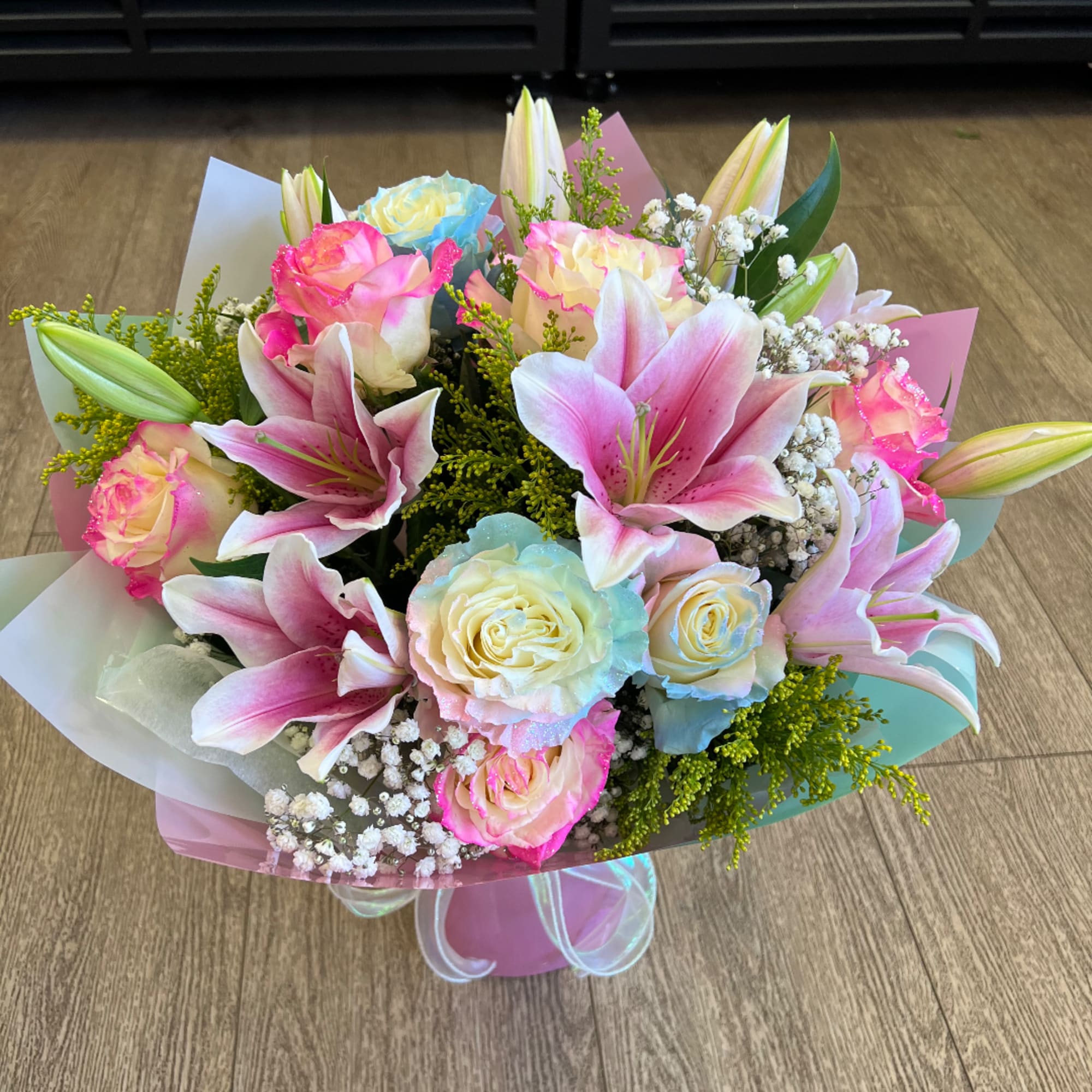 Pastel bouquet of pink lilies and roses wrapped in colored paper