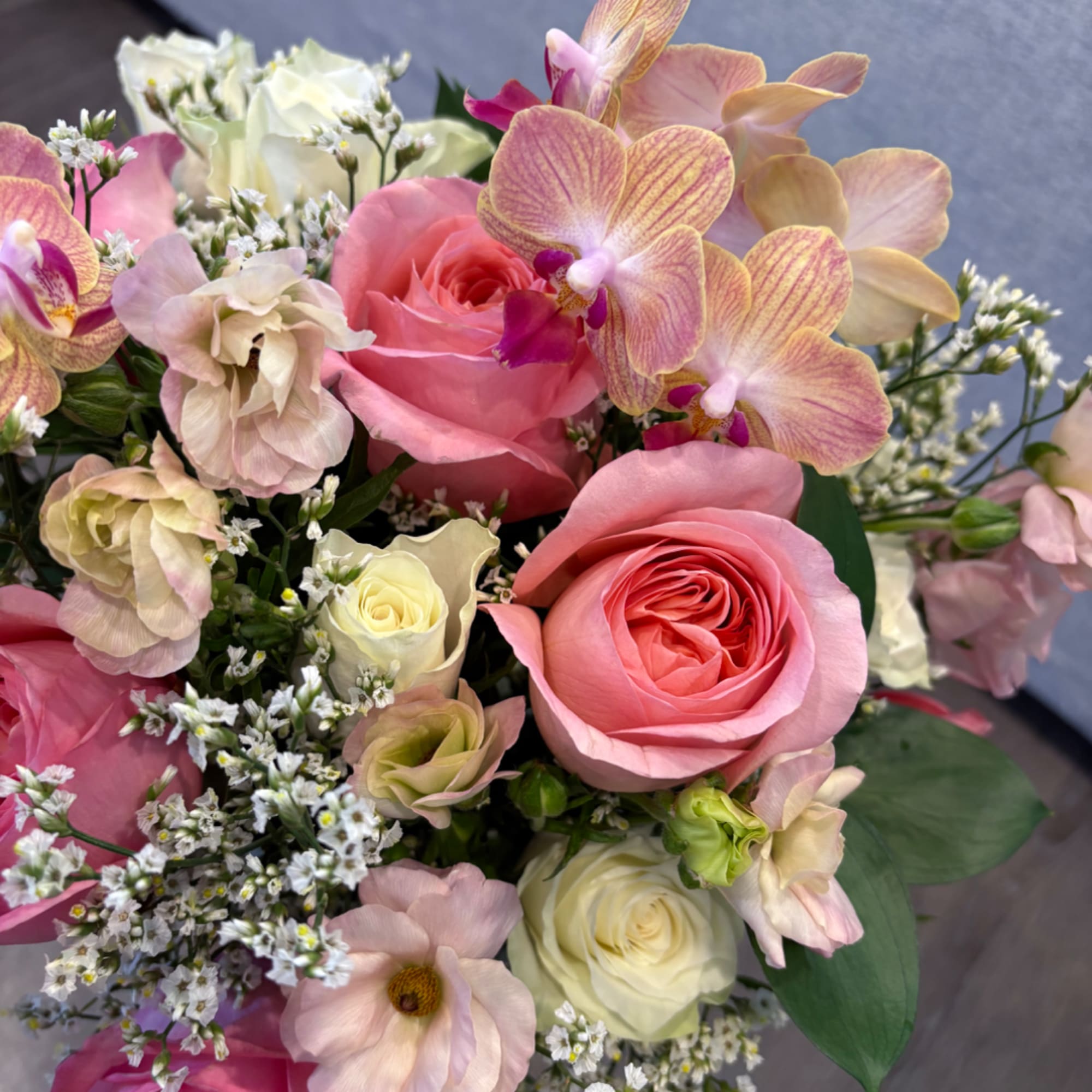 Bouquet of pink and white roses with pale orchids and small filler flowers
