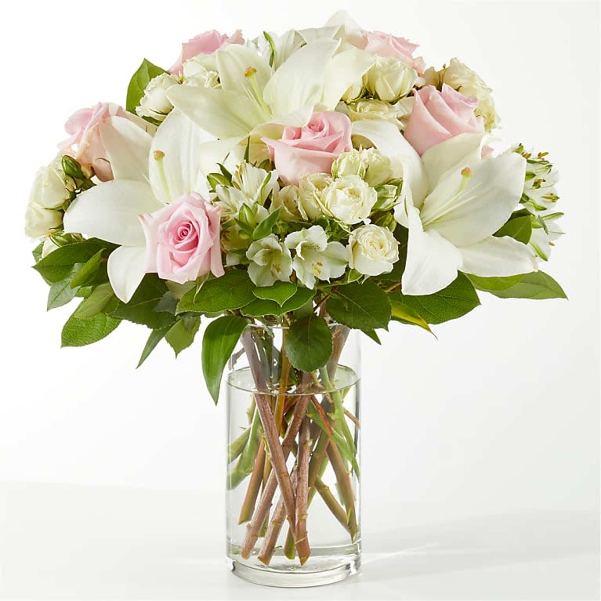 Pink roses and white lilies arranged in a clear glass vase