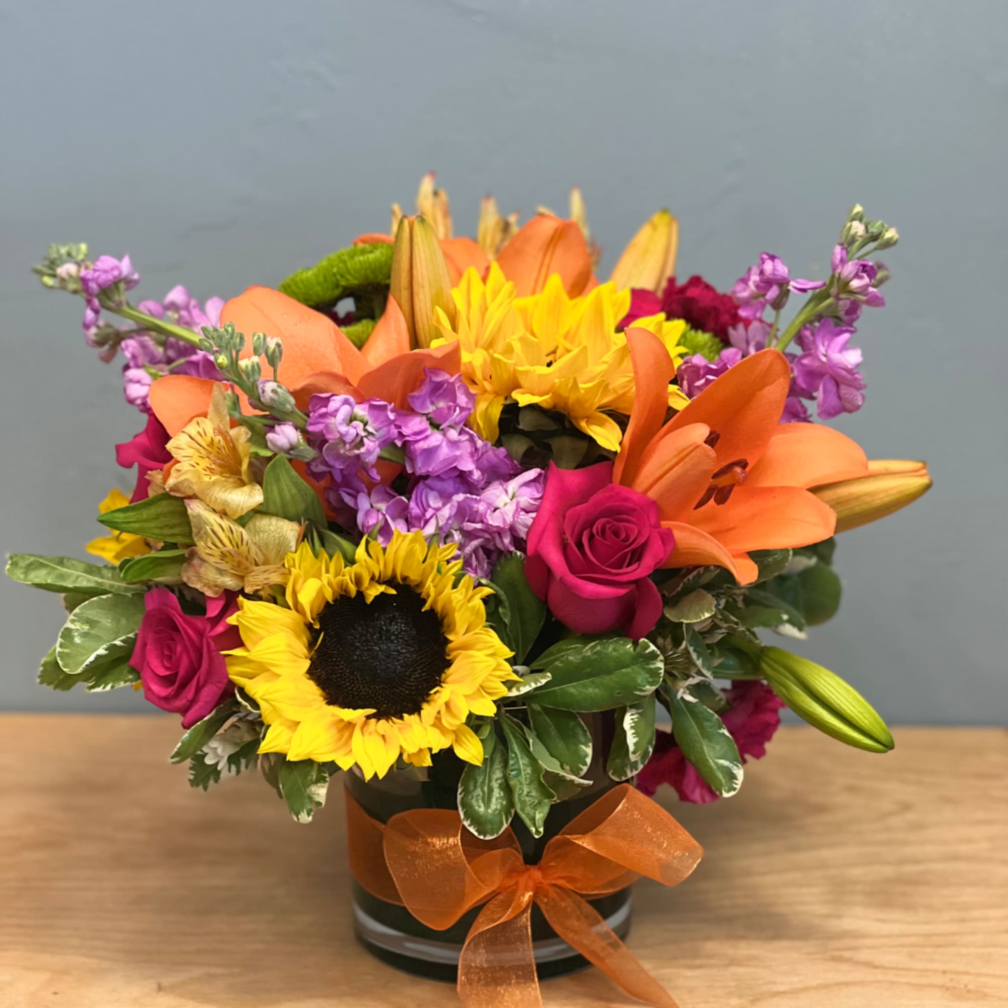 Mixed bouquet with sunflowers, orange lilies, and pink roses in a vase
