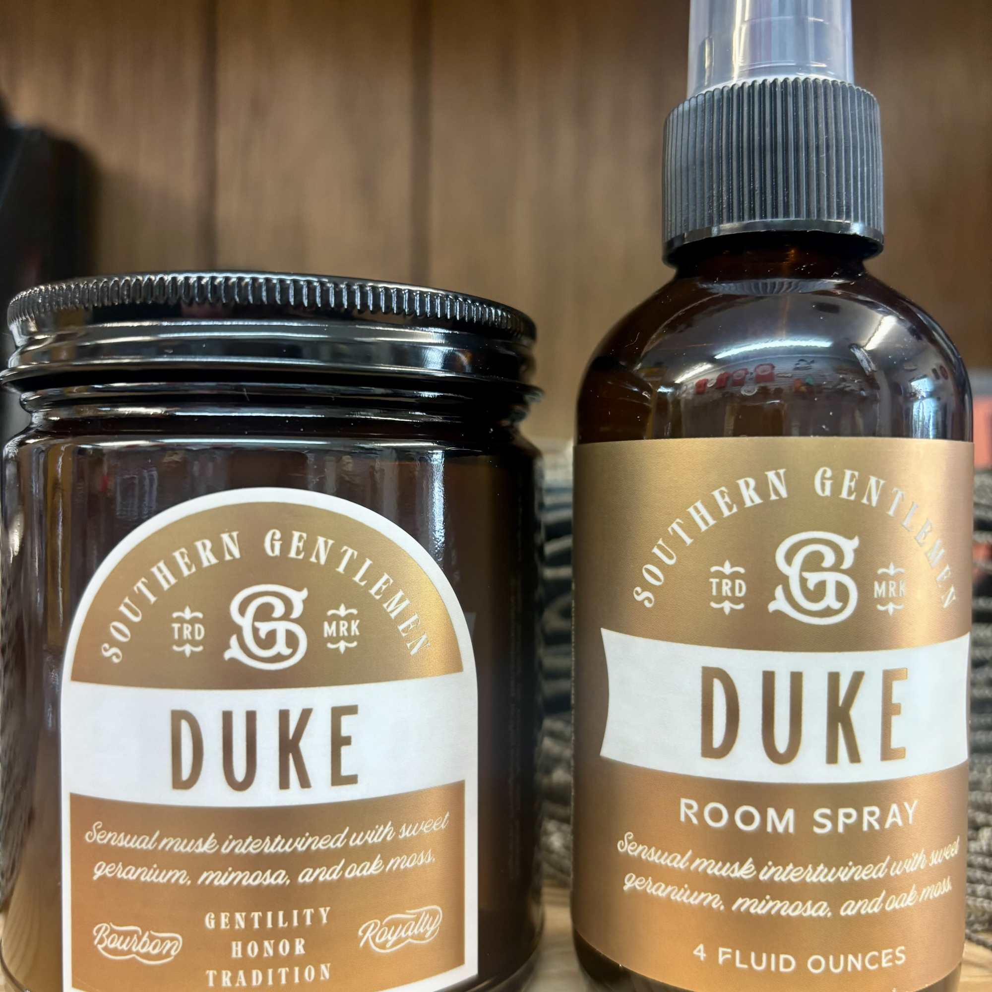Two amber room spray products with gold labels on a wooden shelf