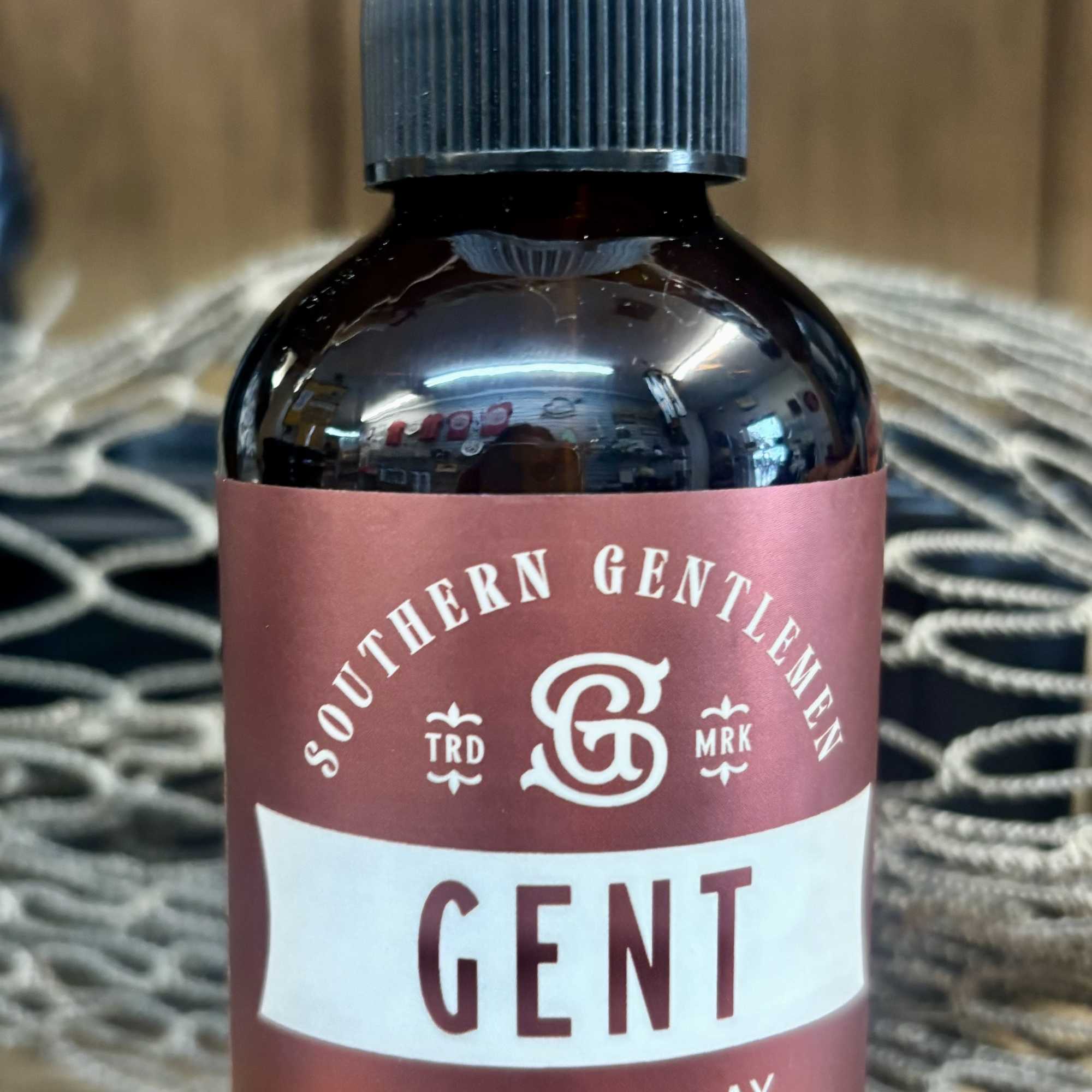 Brown room spray bottle with a clear cap and maroon label