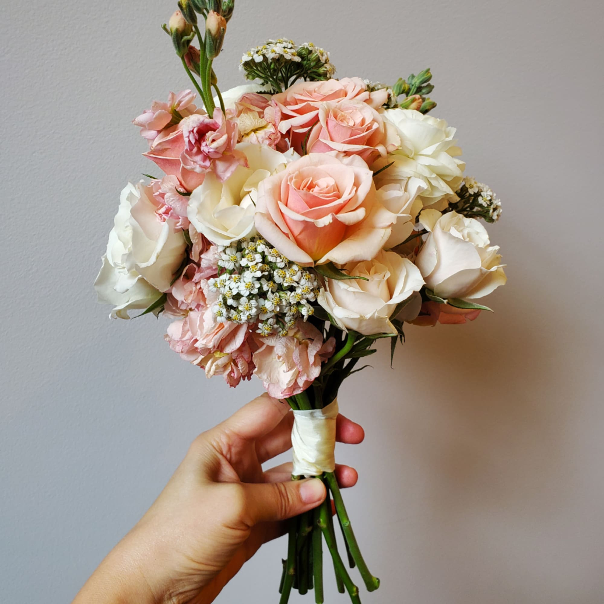 Handheld bouquet of blush and white roses with small filler flowers, photo 3 of 3
