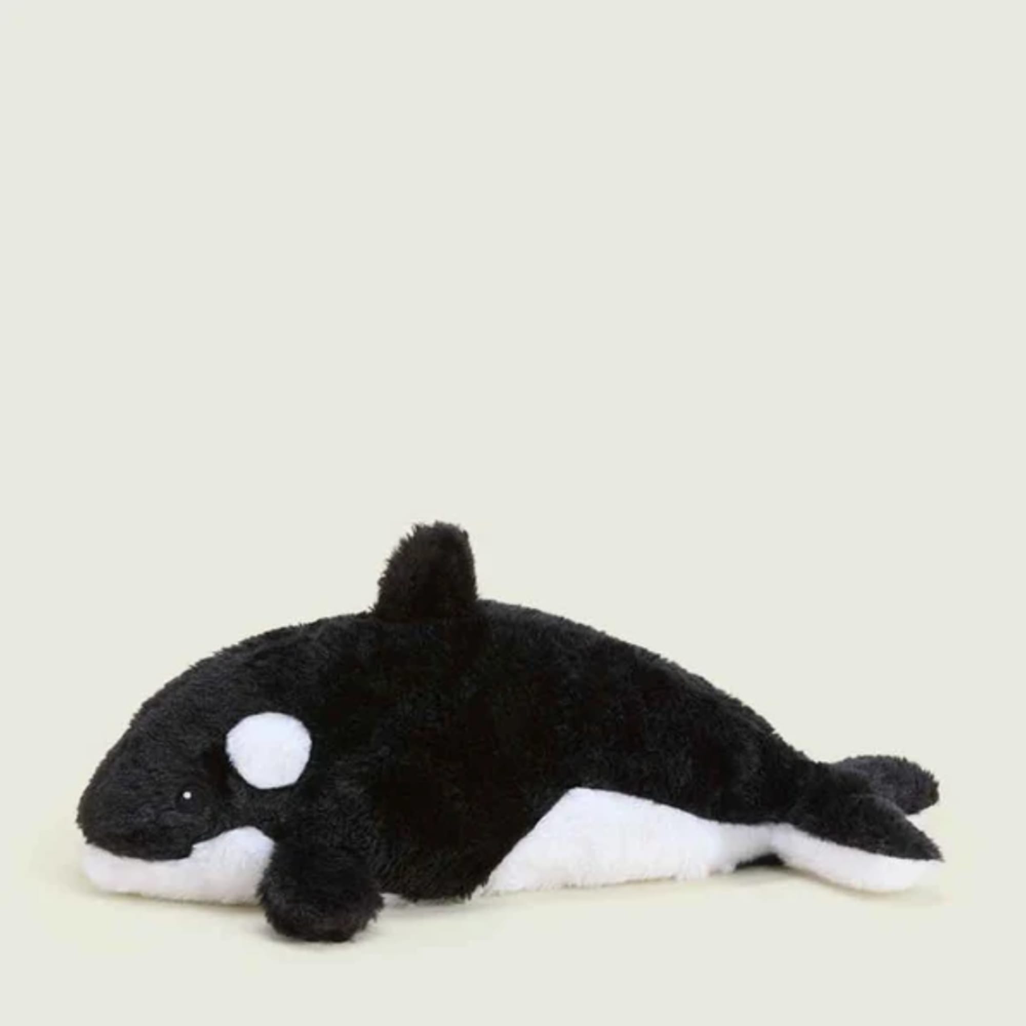 Black-and-white plush orca whale toy on a plain background