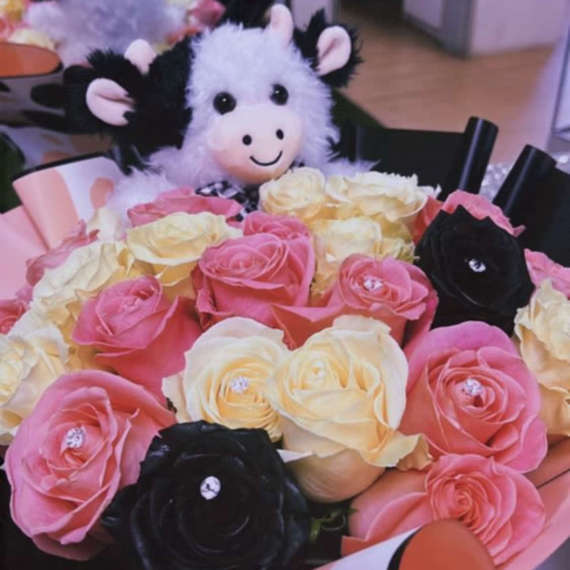 Bouquet of pink, cream, and black roses with a plush cow toy