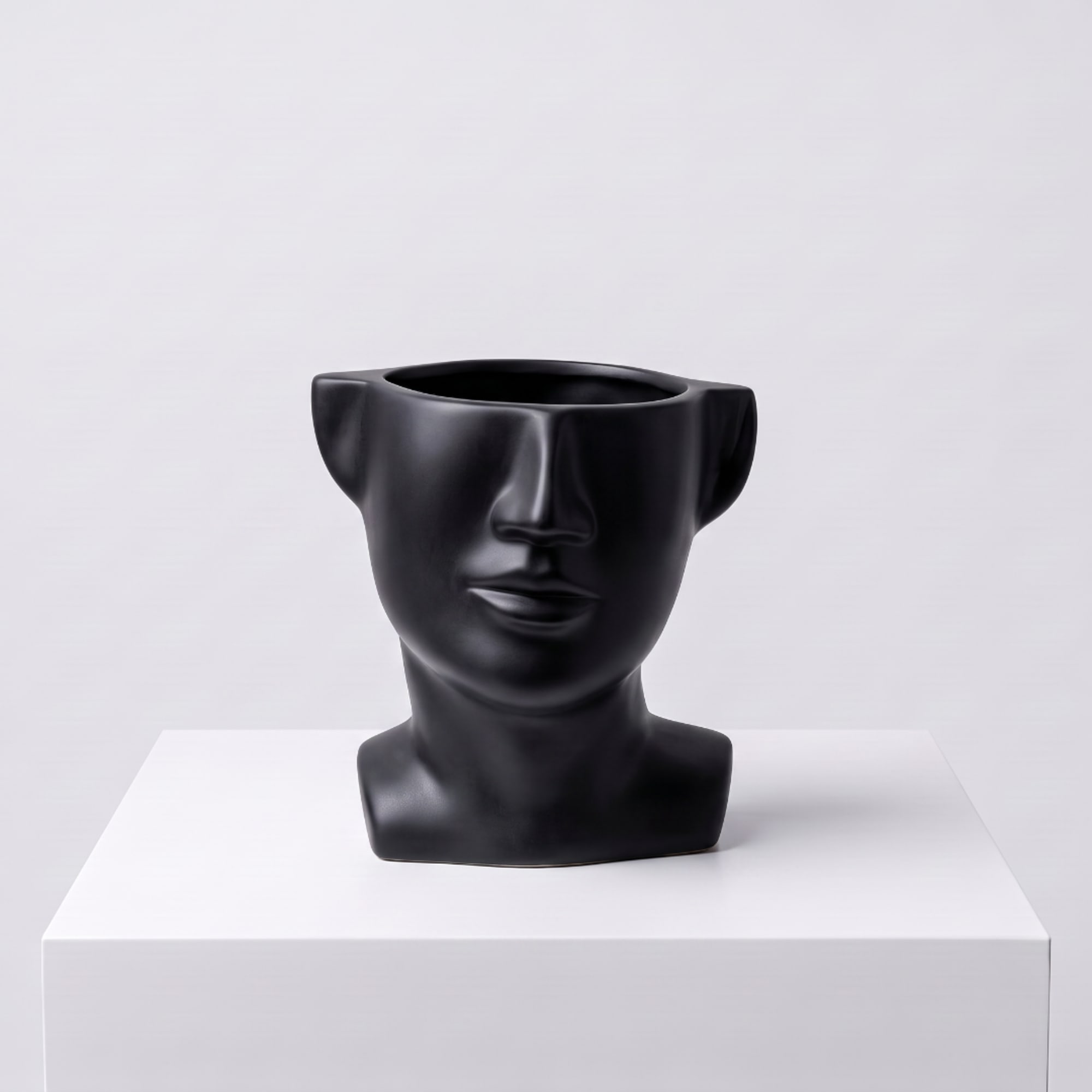 Black face-shaped vase on a white pedestal