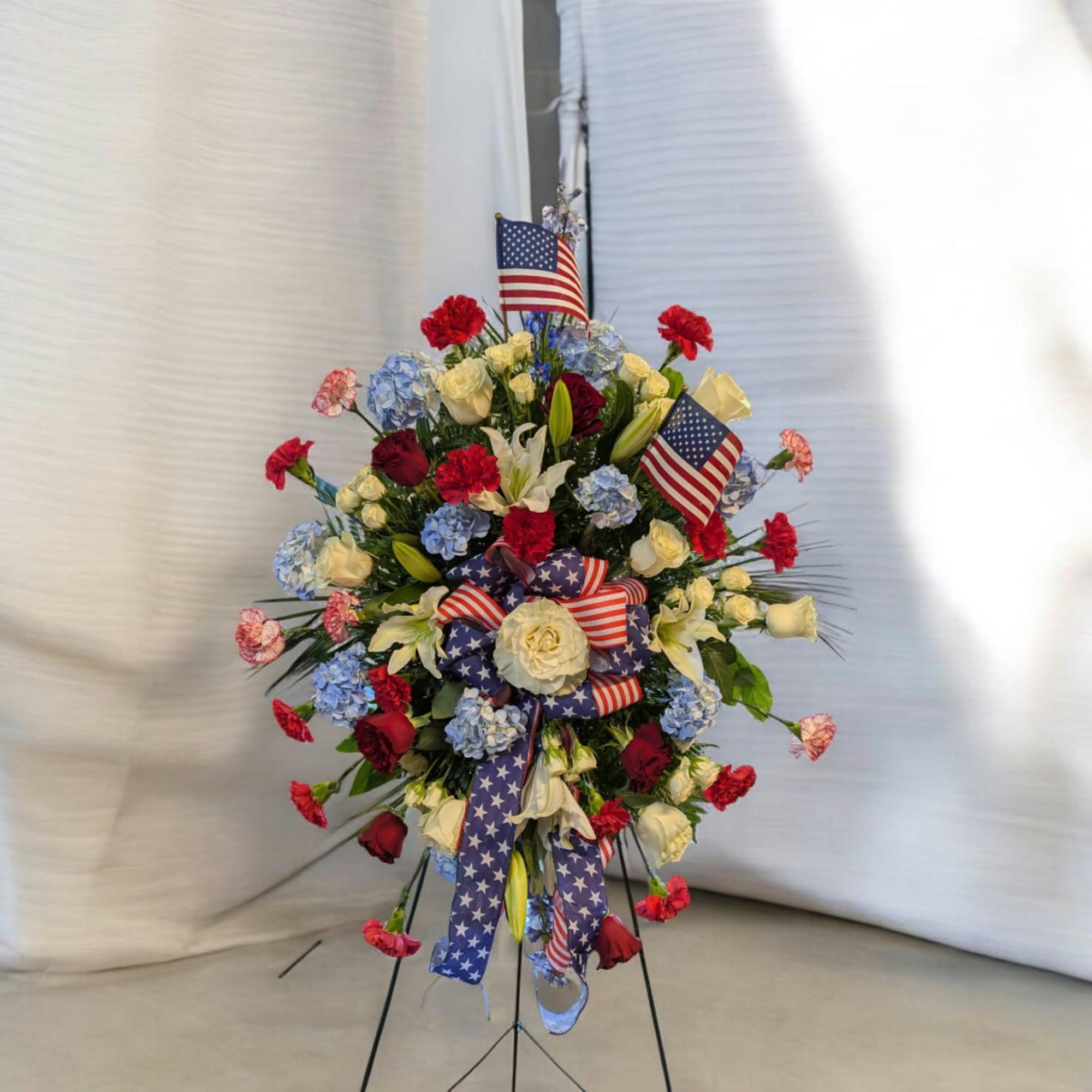 Standing floral spray with red, white, and blue flowers and American flags
