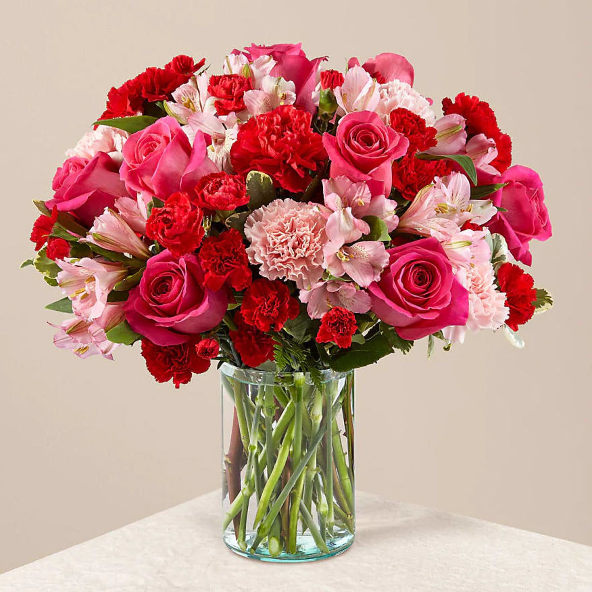 Pink and red bouquet of roses, carnations, and alstroemeria in a glass vase