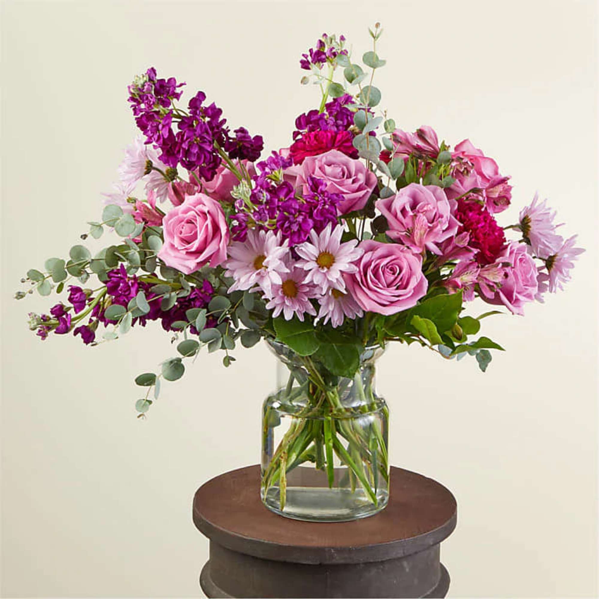 Pink roses and purple flowers arranged in a glass vase