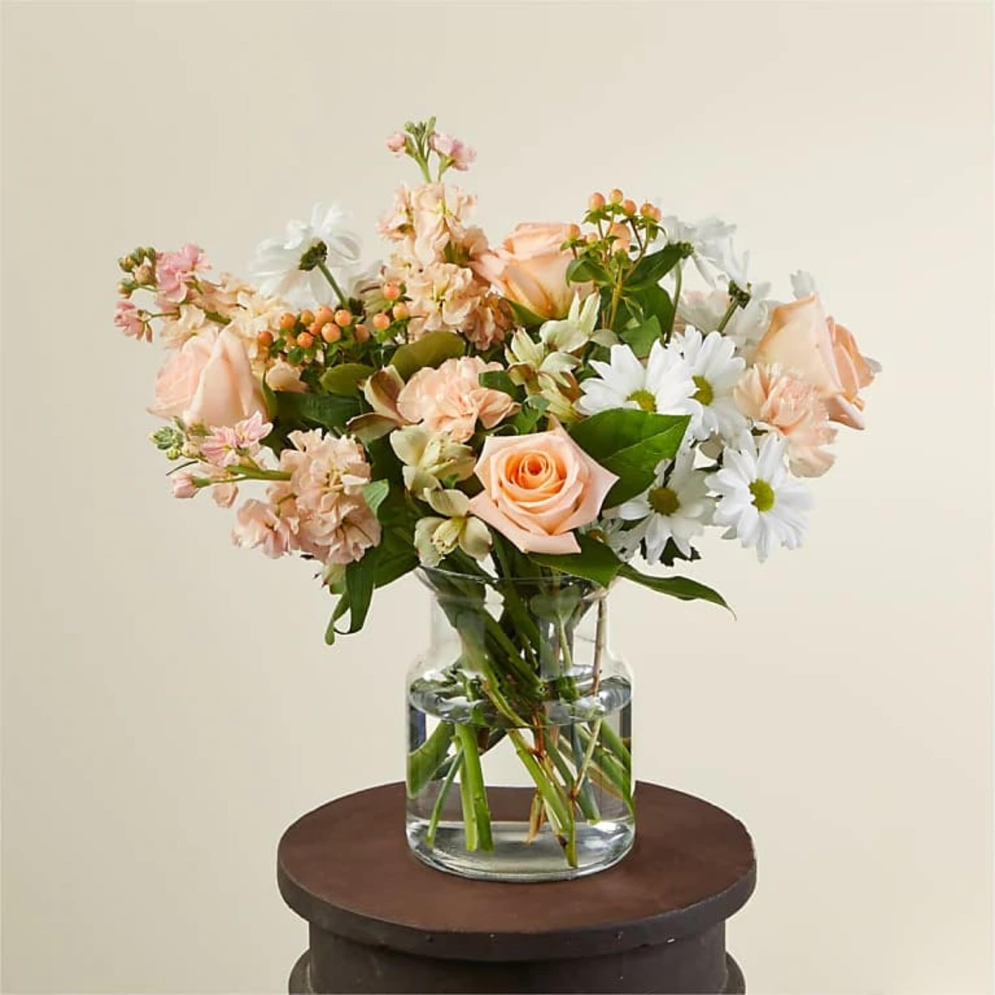 Peach and white mixed bouquet in a clear glass vase