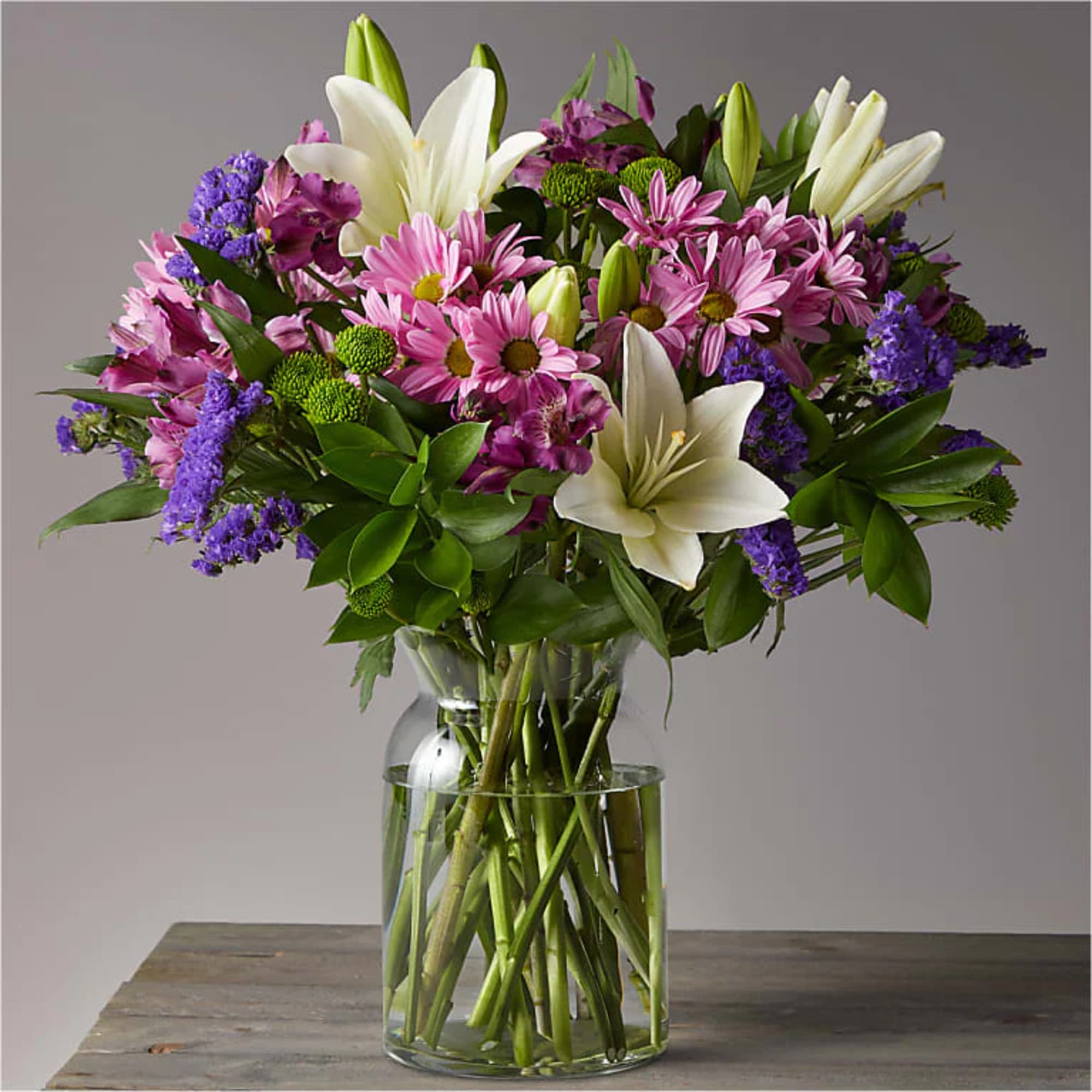 Pink daisies and white lilies in a clear glass vase