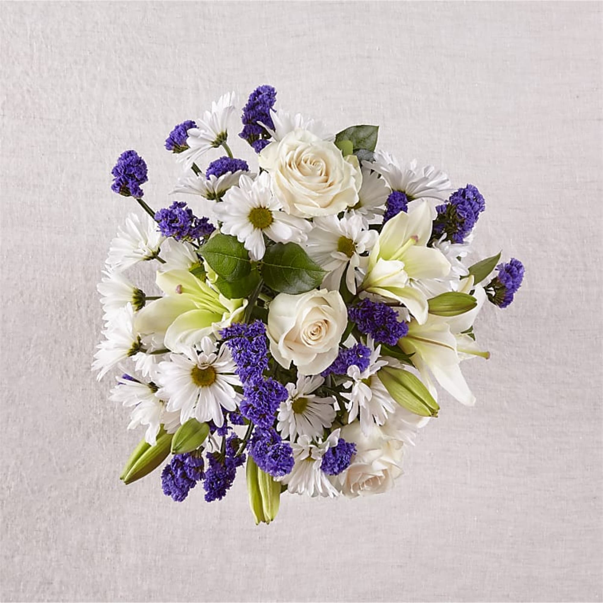 Bouquet of white roses, daisies, lilies, and purple filler flowers