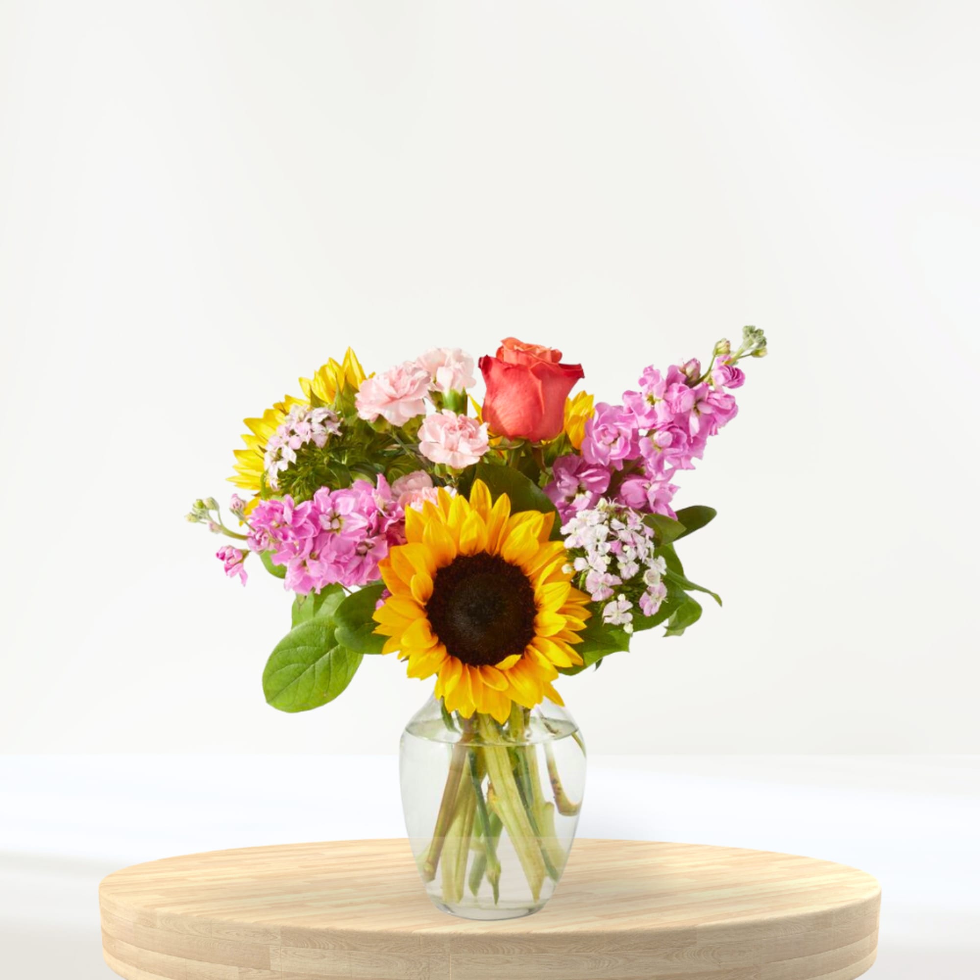 Mixed bouquet with a sunflower and rose in a clear glass vase