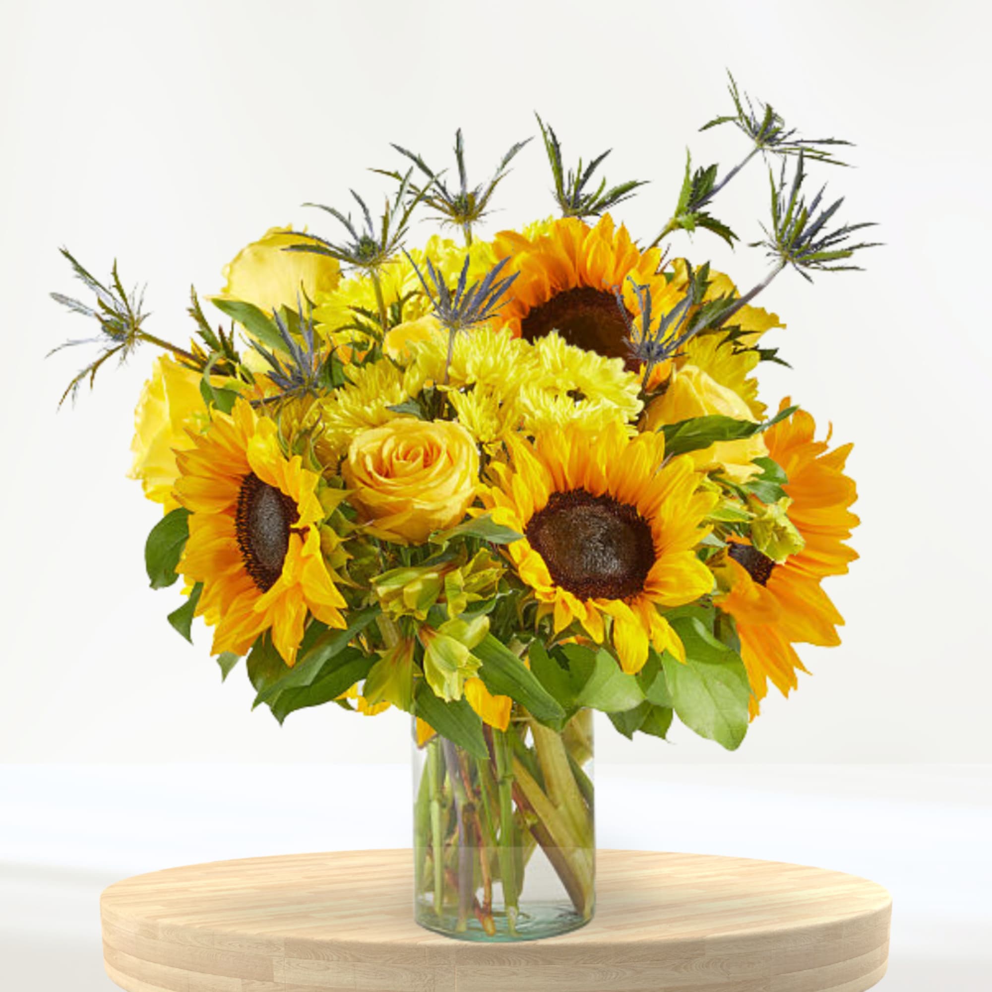 Sunflower and yellow rose bouquet in a clear glass vase