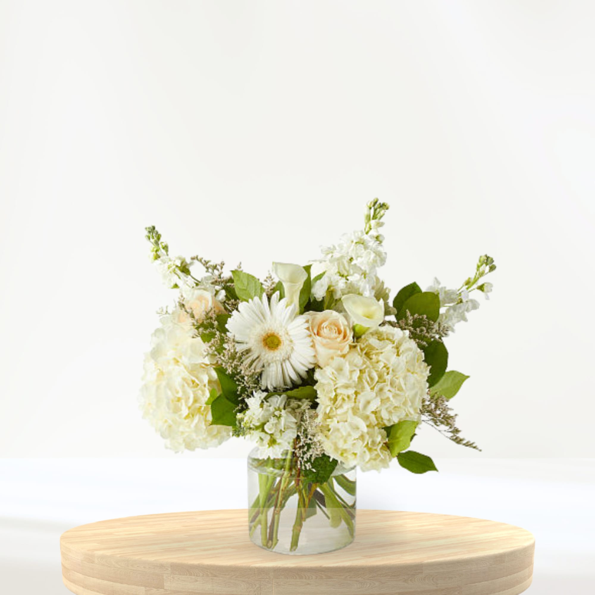 White floral arrangement in a clear glass vase on a wooden table