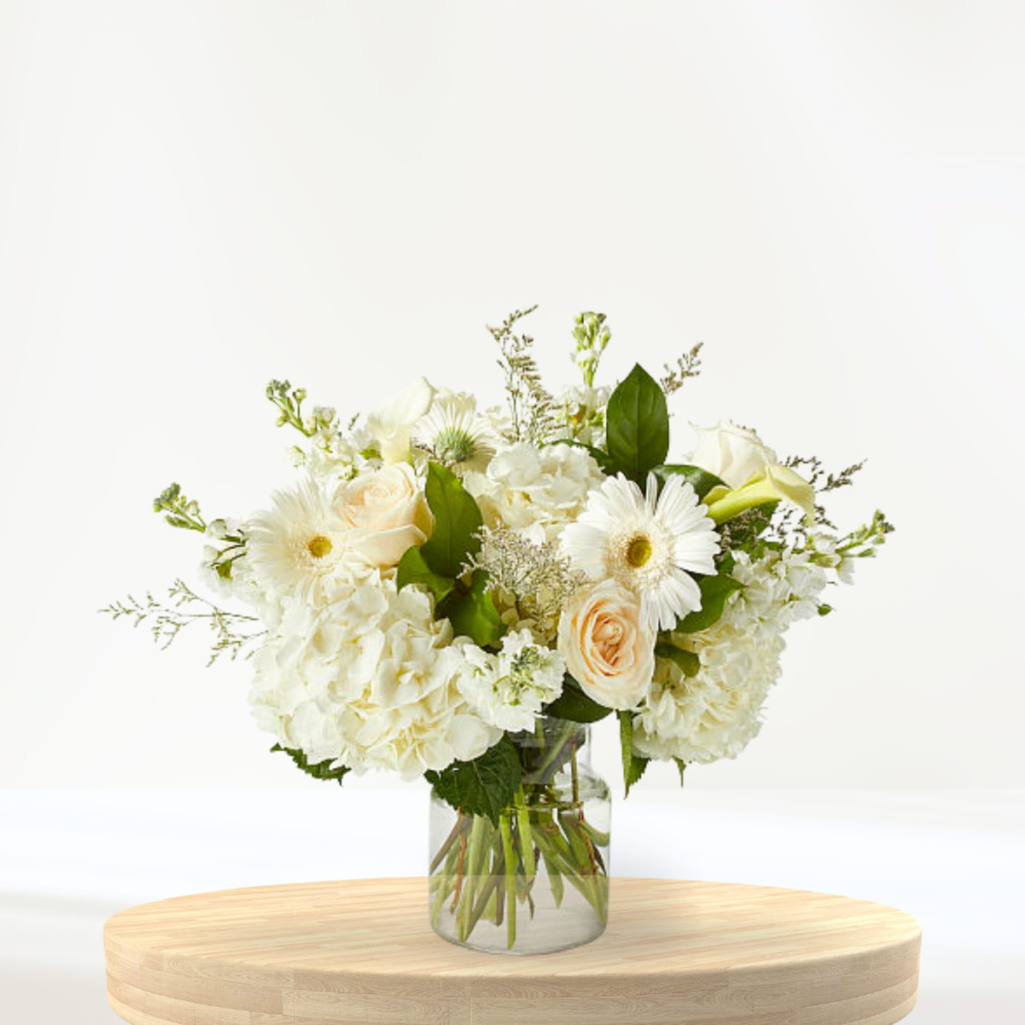 White floral bouquet in a clear glass vase on a wooden table