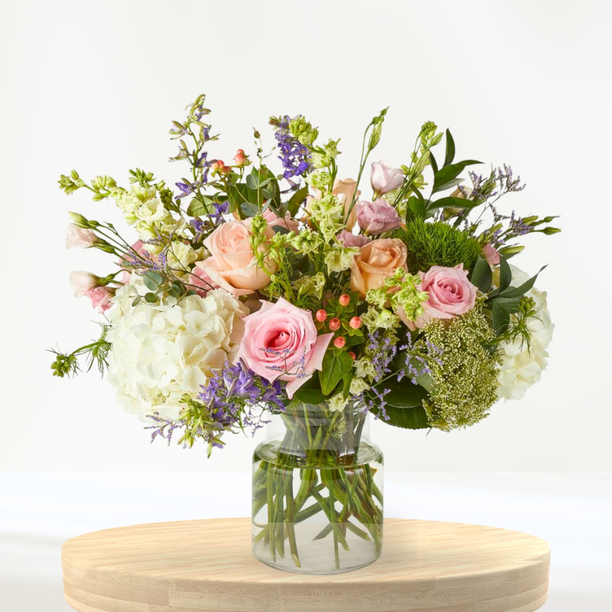 Mixed bouquet of pink and peach roses in a clear glass vase